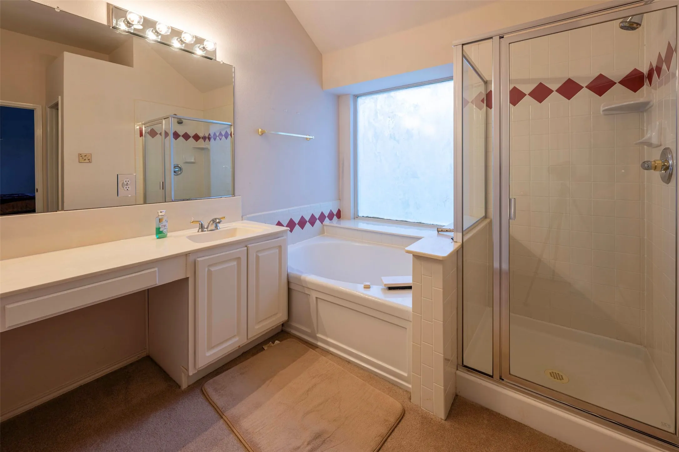 Bathroom featuring a built-in soaking tub, a separate glass-enclosed shower, a vanity with integrated sink, and an expansive mirror