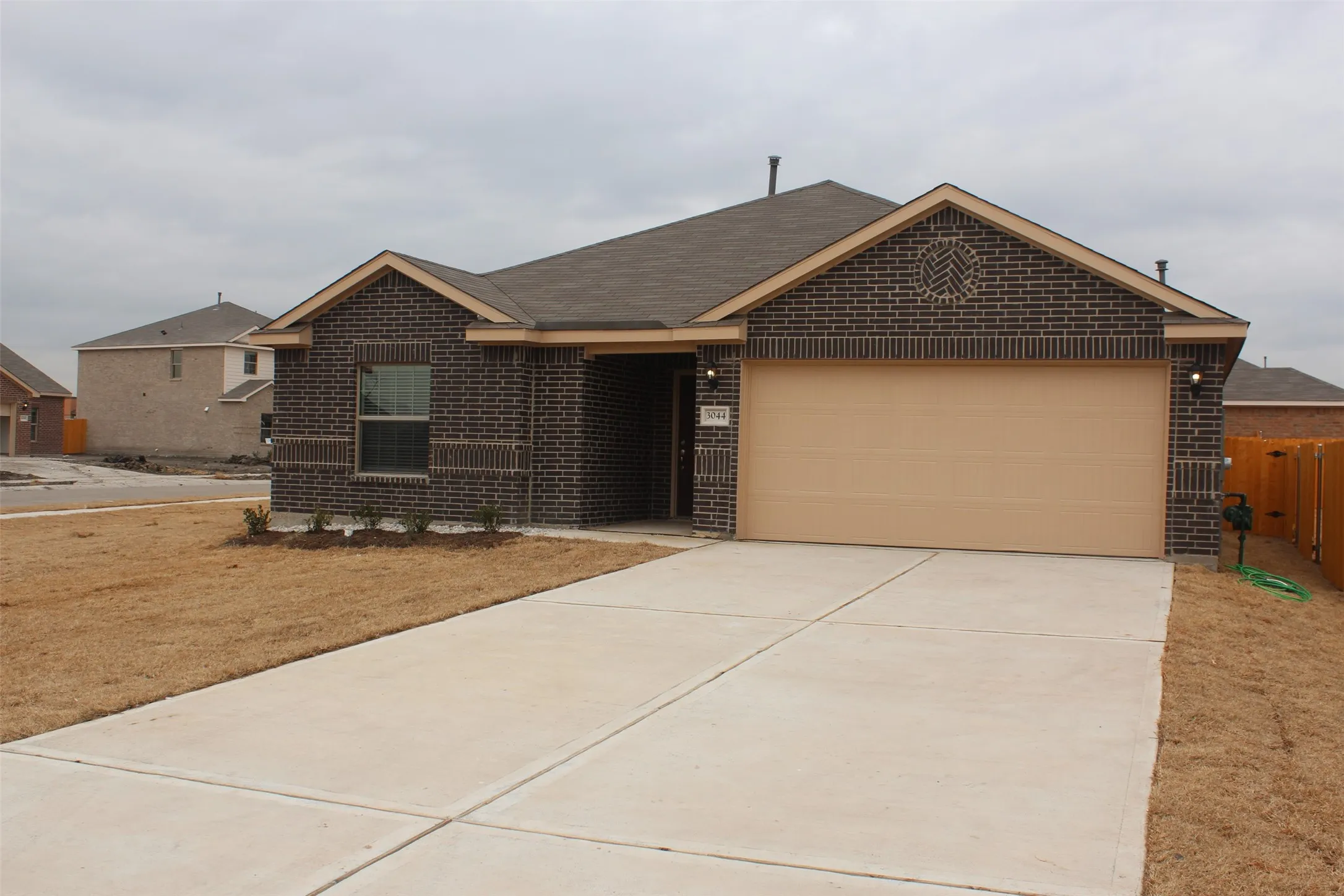 Dark brick exterior with a tan garage door and contrasting light trim