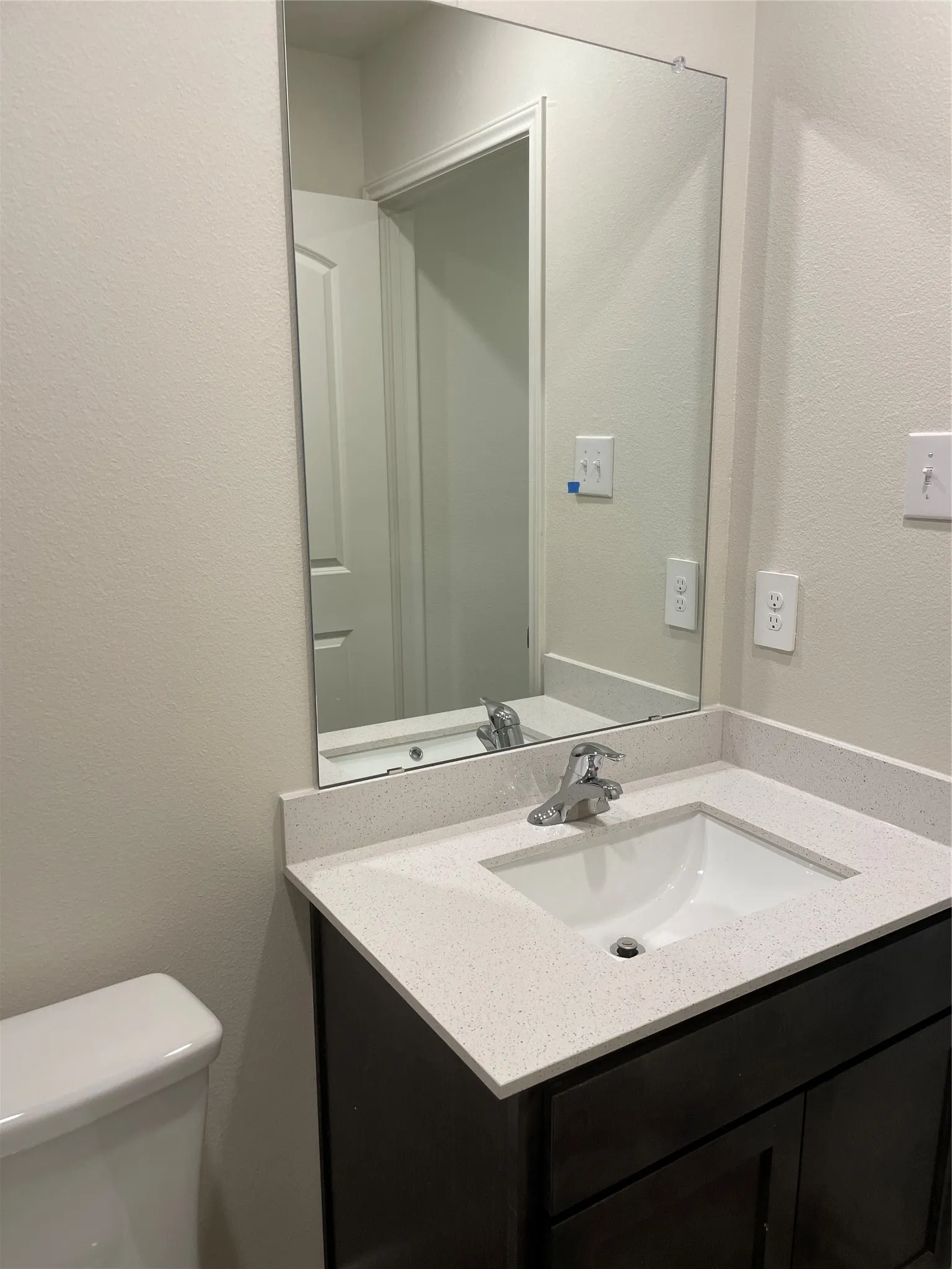 Bathroom vanity featuring a dark wood-finish cabinet with a white quartz-finish countertop and an undermount sink