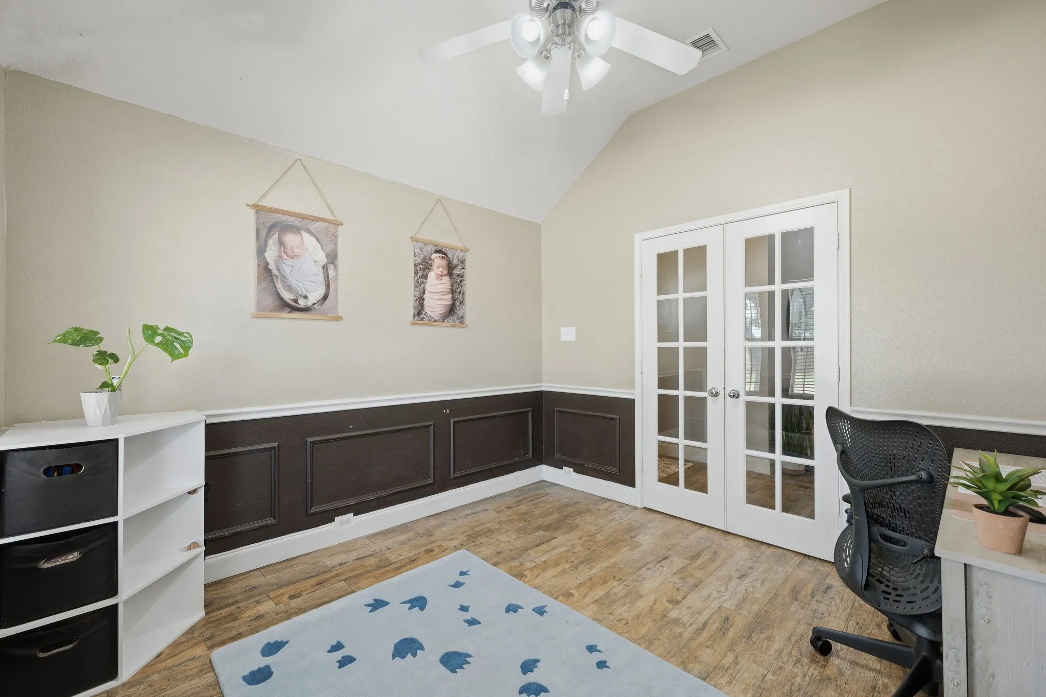 Vaulted ceiling room featuring French doors with multiple lites, wood-finish flooring, and a ceiling fan