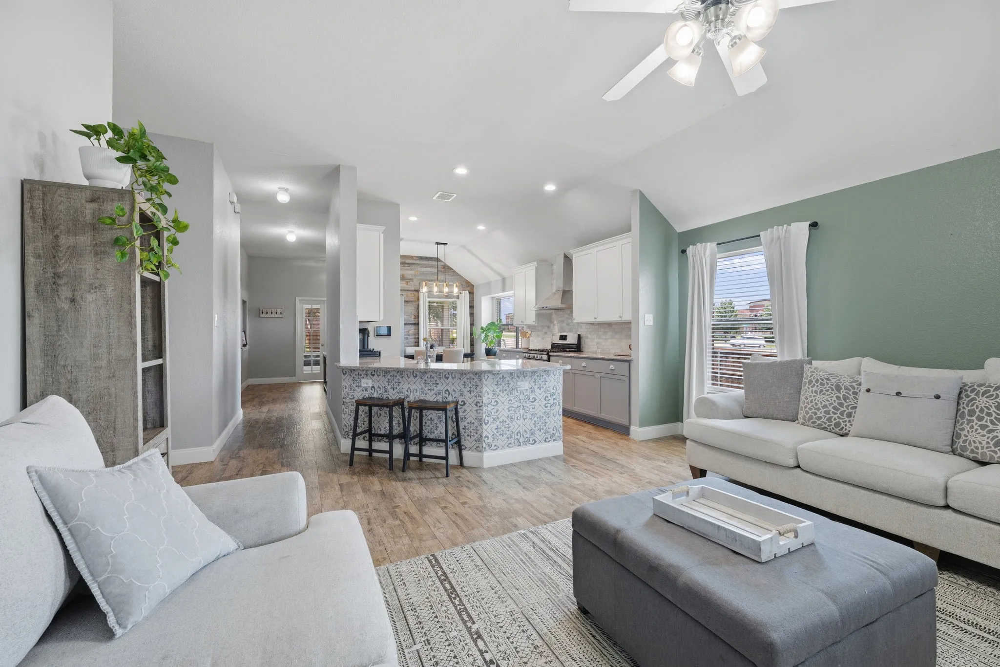 Open-concept living area with vaulted ceiling, wood-finish flooring, and a ceiling fan with integrated lighting
