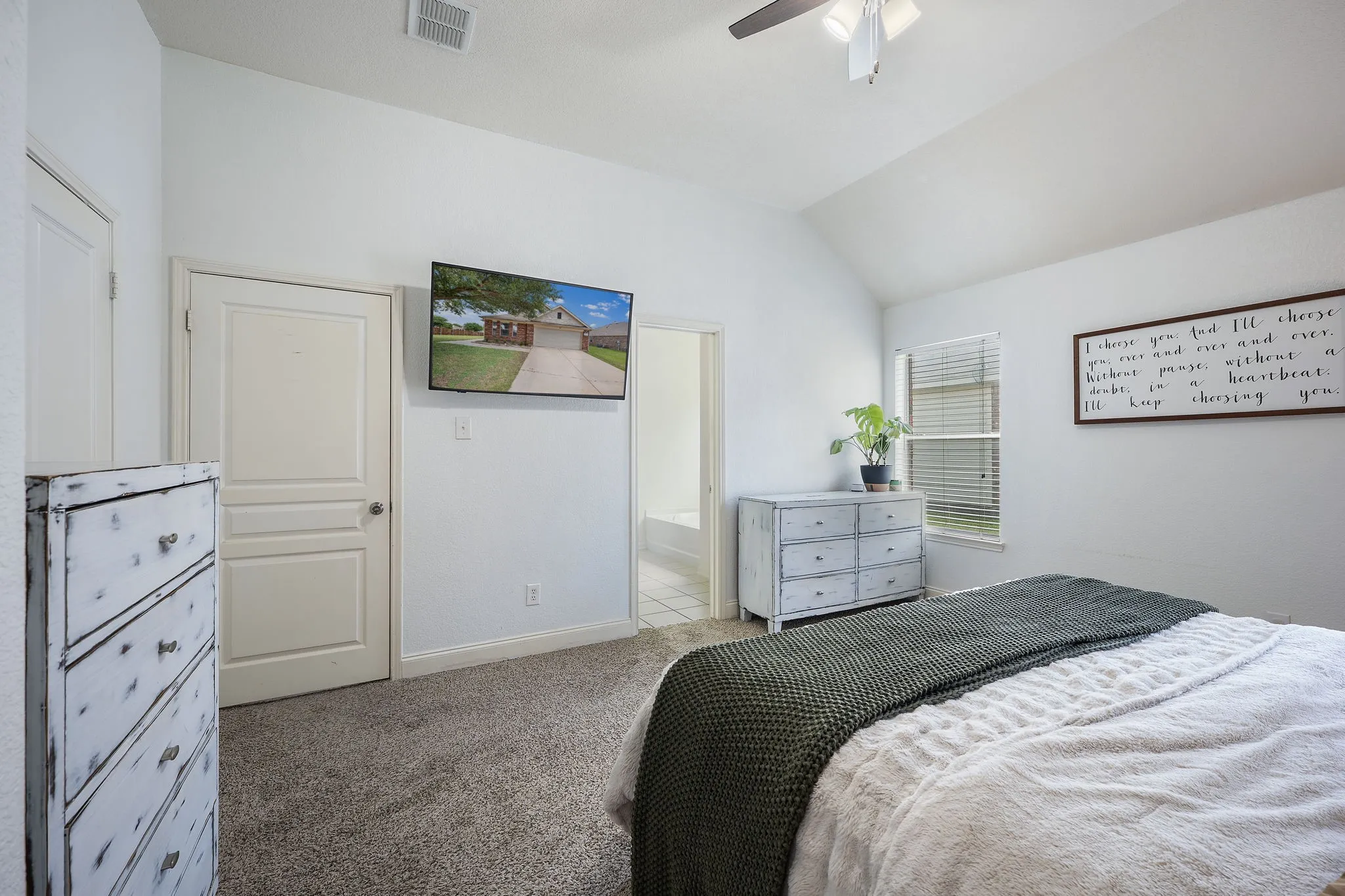 Vaulted ceiling bedroom featuring carpeting, a ceiling fan with light fixture, a window with blinds, and white interior doors