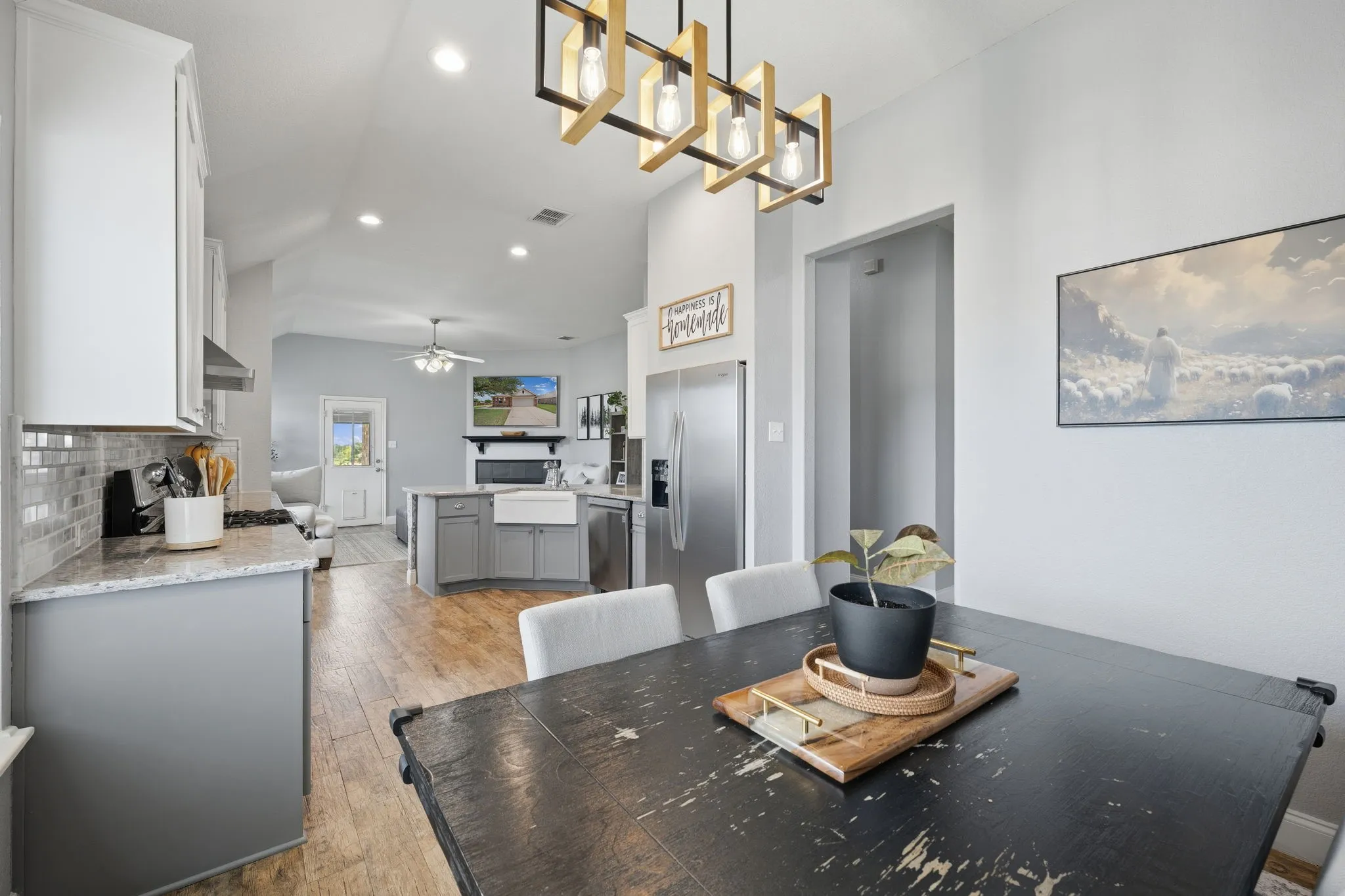 Open-concept kitchen and dining area featuring a vaulted ceiling and wood-finish flooring