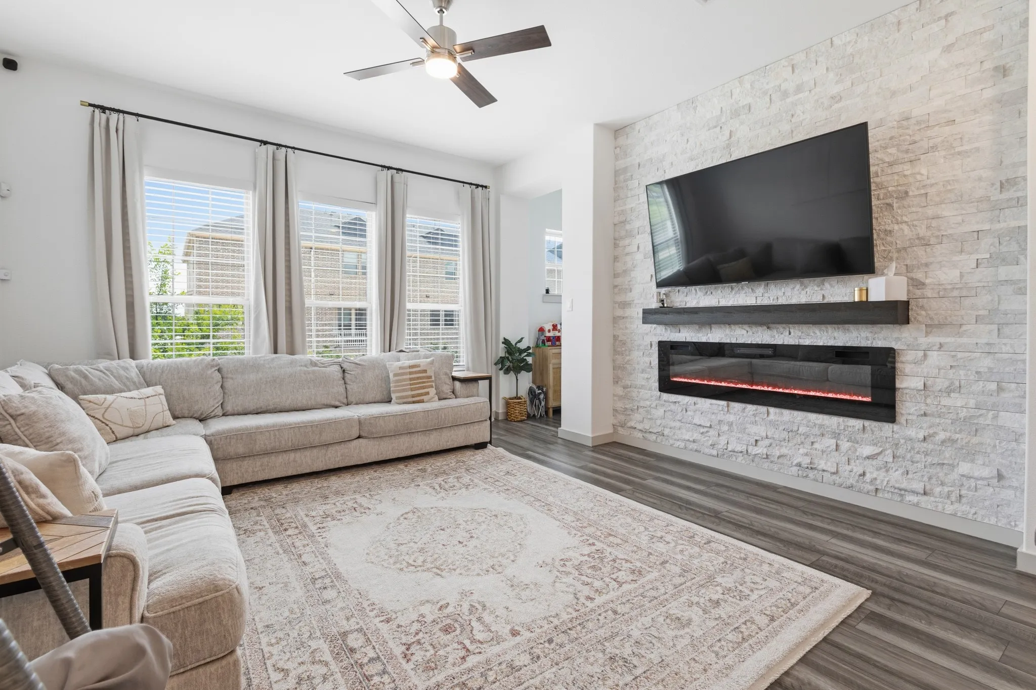 The showstopping main level centers around a dramatic 10x10 stone fireplace flanked by designer light fixtures and a sophisticated open-concept layout flowing seamlessly to dining and kitchen.