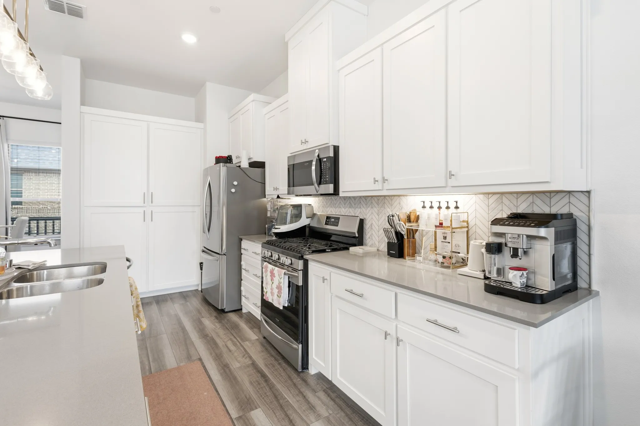 Chef-inspired kitchen featuring white shaker cabinetry, quartz countertops, stainless steel appliances including a gas cooktop, subway tile backsplash, and a generously sized island.