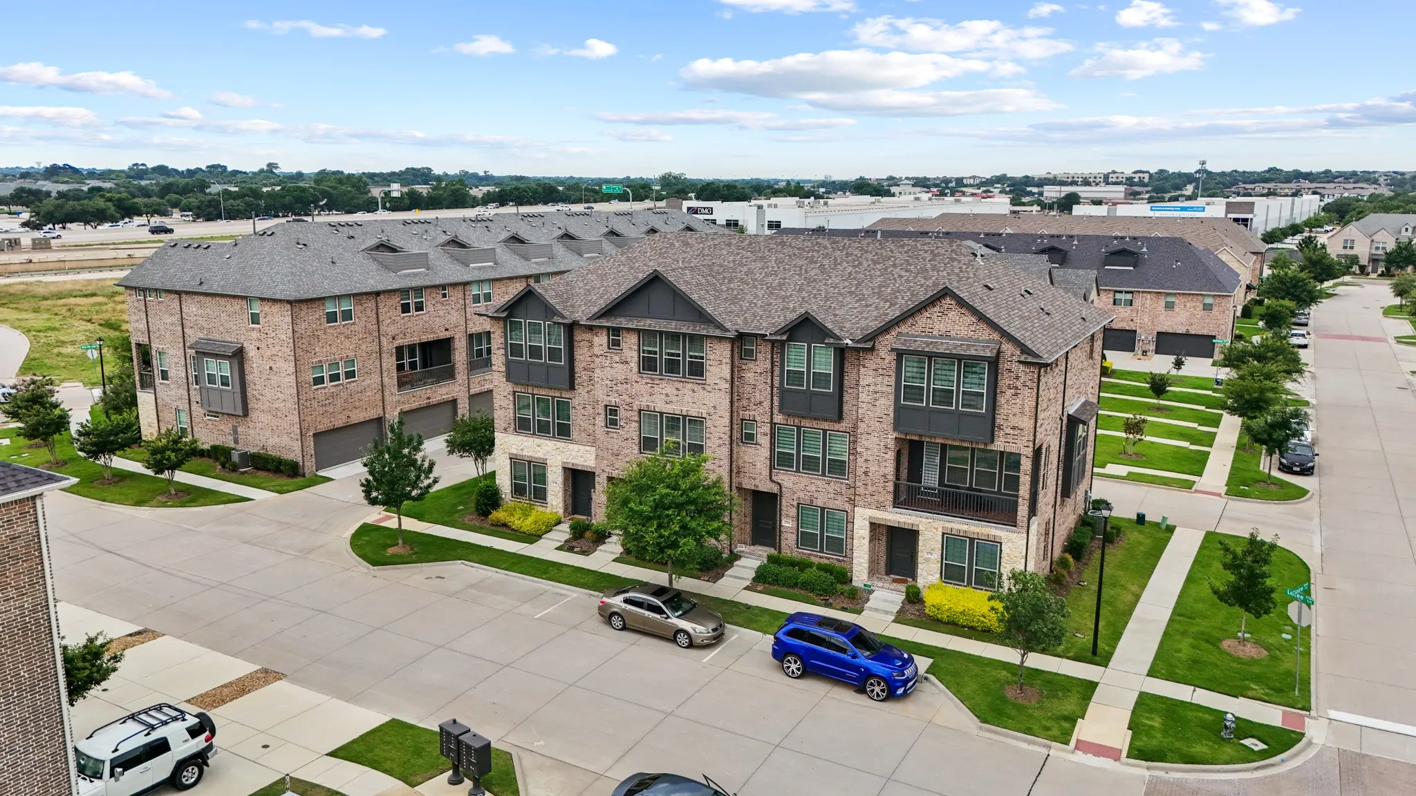 Aerial view of the Vista Del Lago community showcasing the beautifully landscaped streets, quality brick townhomes, and prime Lewisville location near Hwy 121 and major amenities.