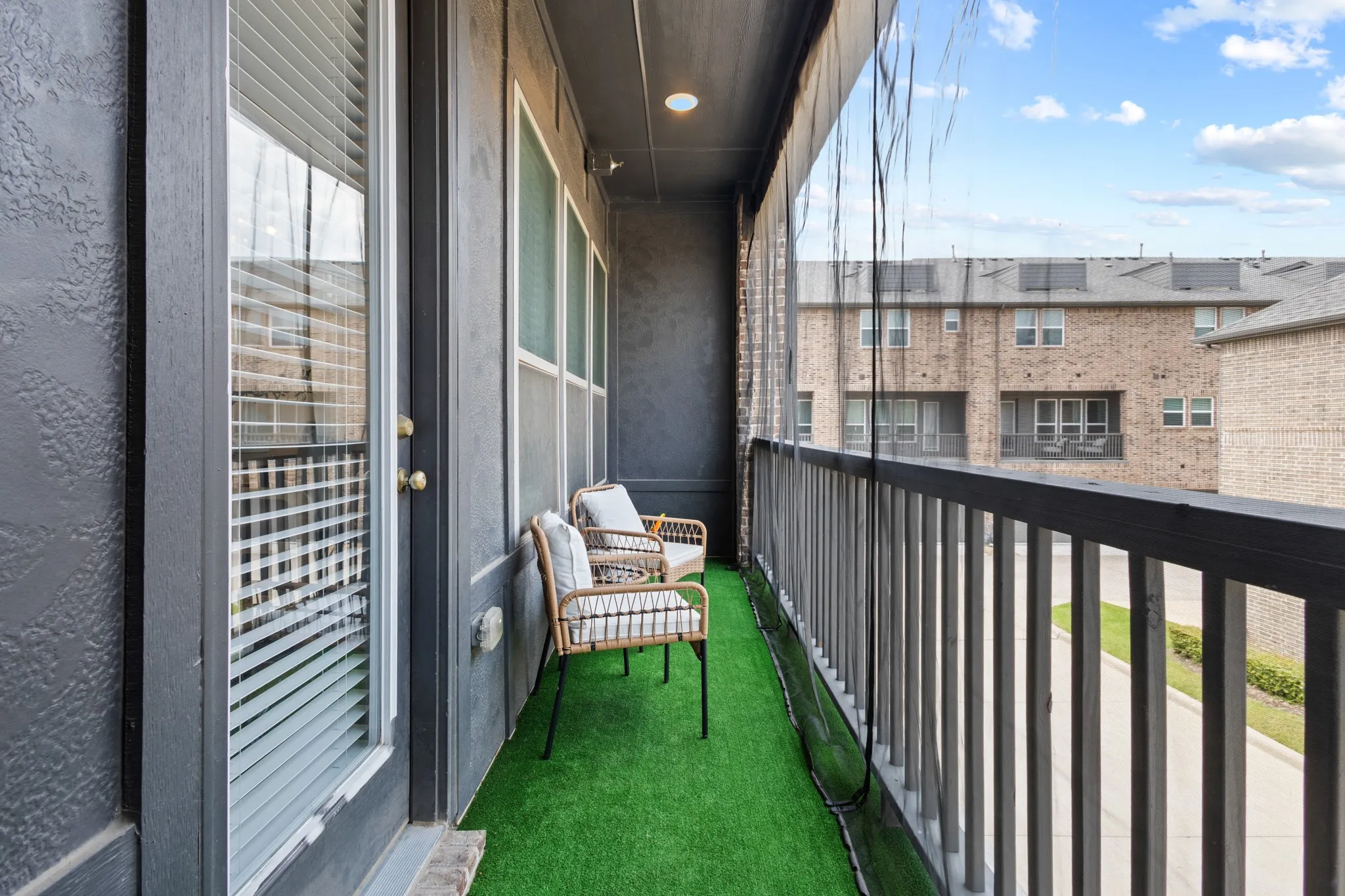 Covered balcony with premium artificial turf and patio seating, offering a tranquil outdoor extension of your living space with serene views of the Vista Del Lago community.
