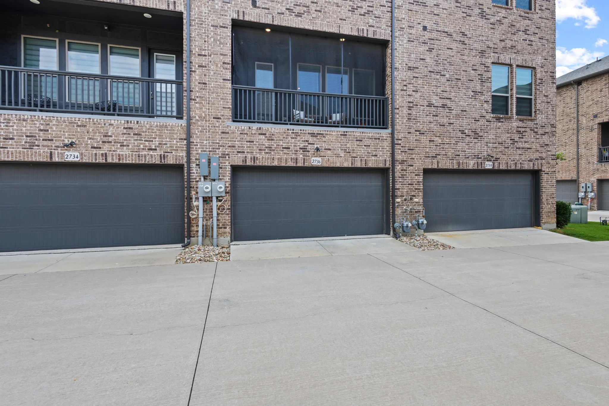 Street-level view of 2736 Levee Lane showcasing the premium brick facade, oversized 2-car garage with elevated ceilings, and clean architectural lines of this exceptional townhome.