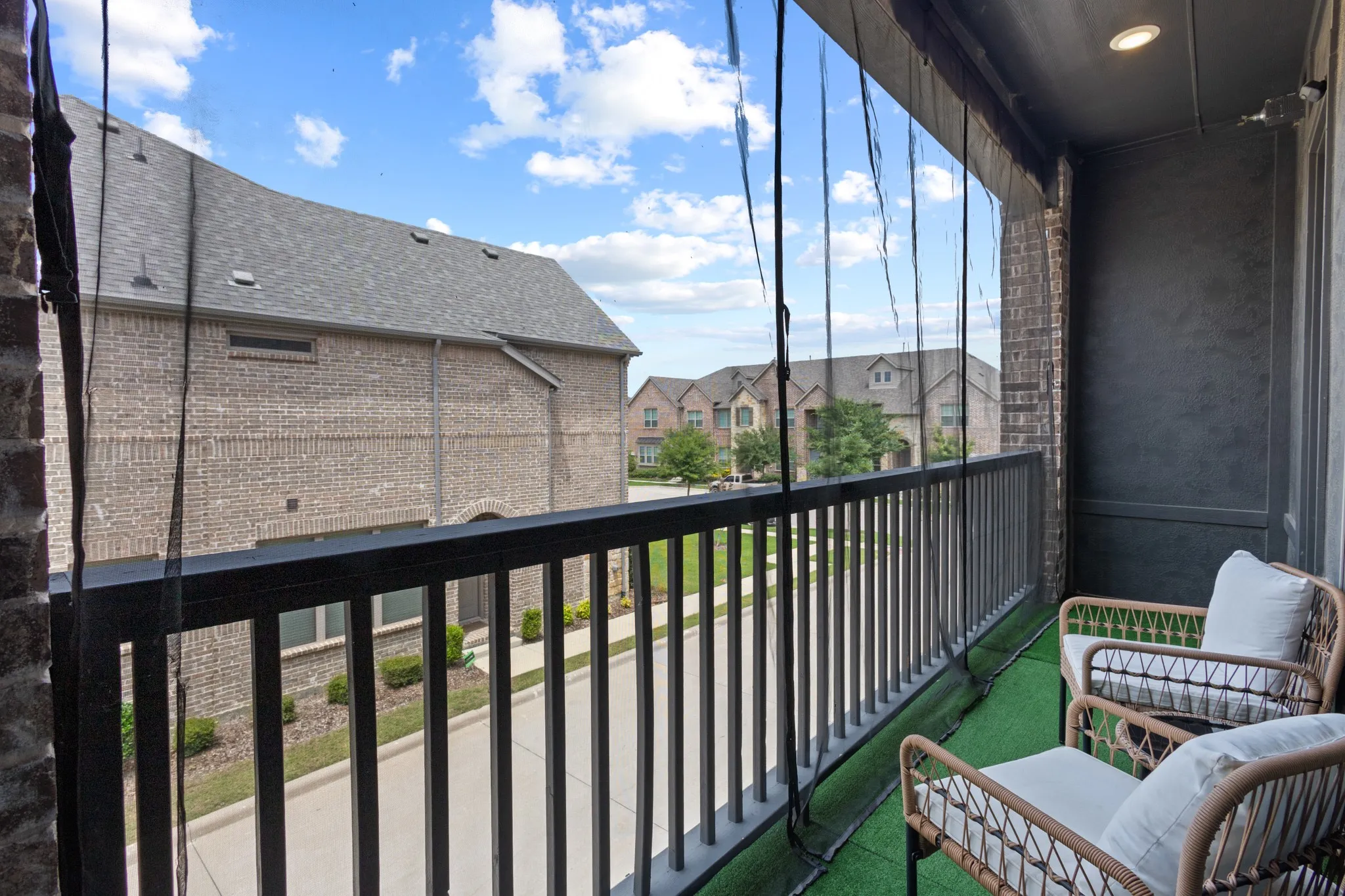 Private main-level balcony featuring artificial turf flooring and sleek black metal railing -- a low-maintenance outdoor retreat perfect for morning coffee or evening relaxation.