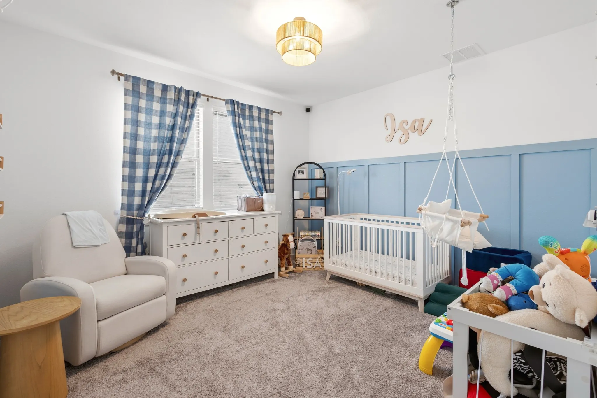 Comfortable secondary bedroom with plush carpeting, charming blue wainscoting, and a playful design -- currently styled as a nursery but adaptable as a guest room or children's room.