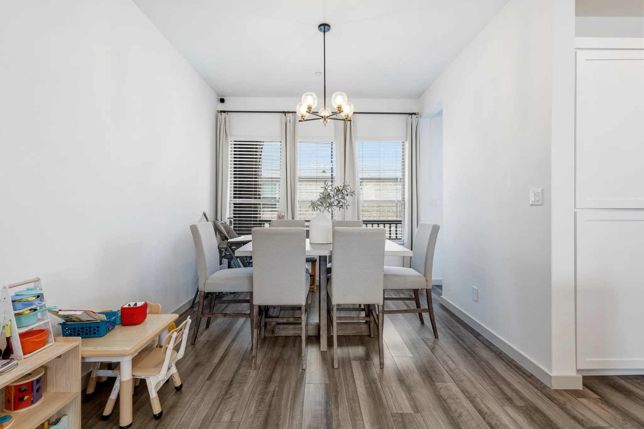 Inviting dining area featuring an elegant chandelier, wood-finish flooring, and an open layout that connects effortlessly to the kitchen and living room -- perfect for hosting family and guests.