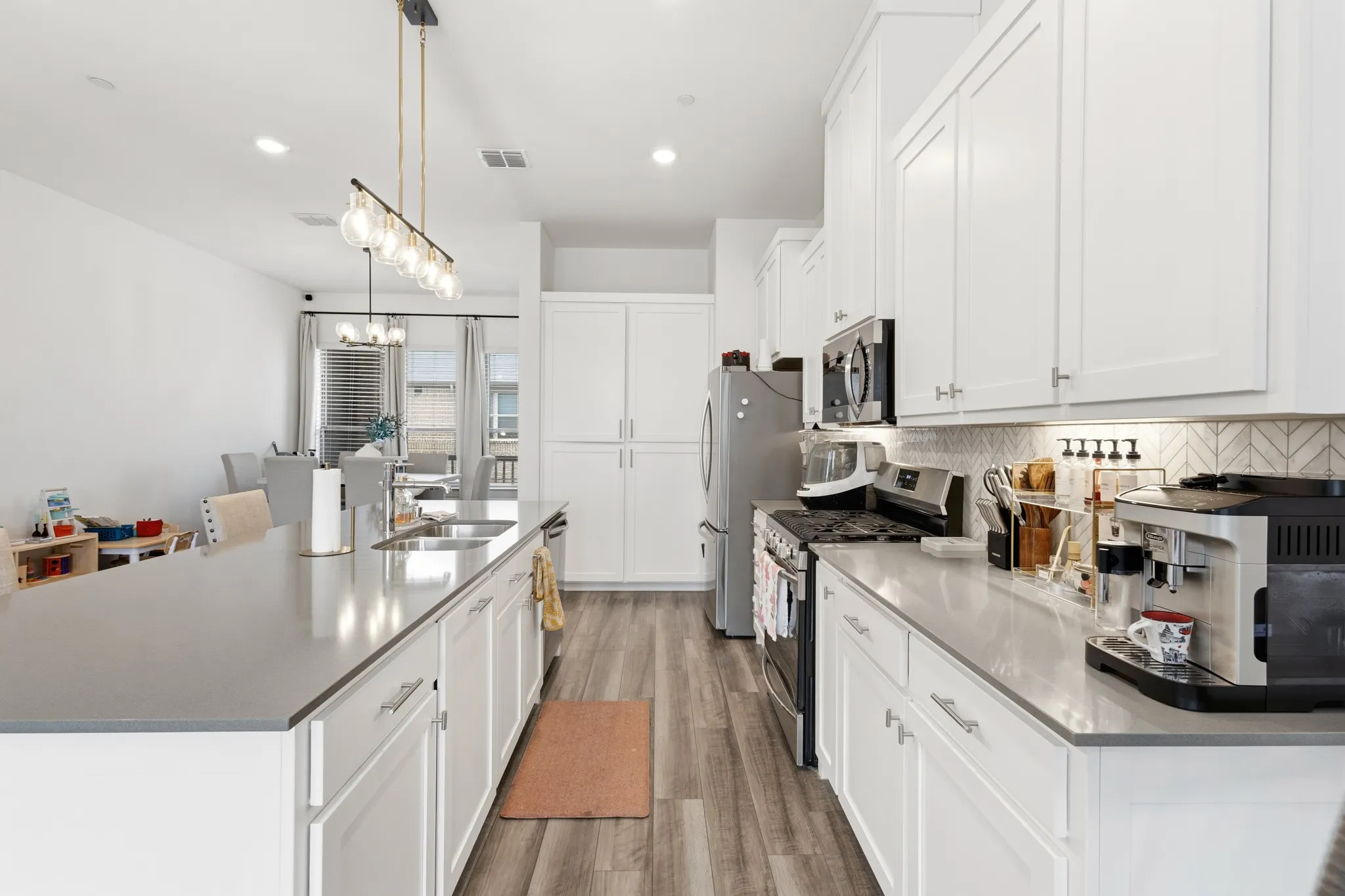 Modern kitchen showcasing pendant lighting over the island, quartz countertops, stainless appliances, and a stylish design that perfectly complements the open-concept living floor.