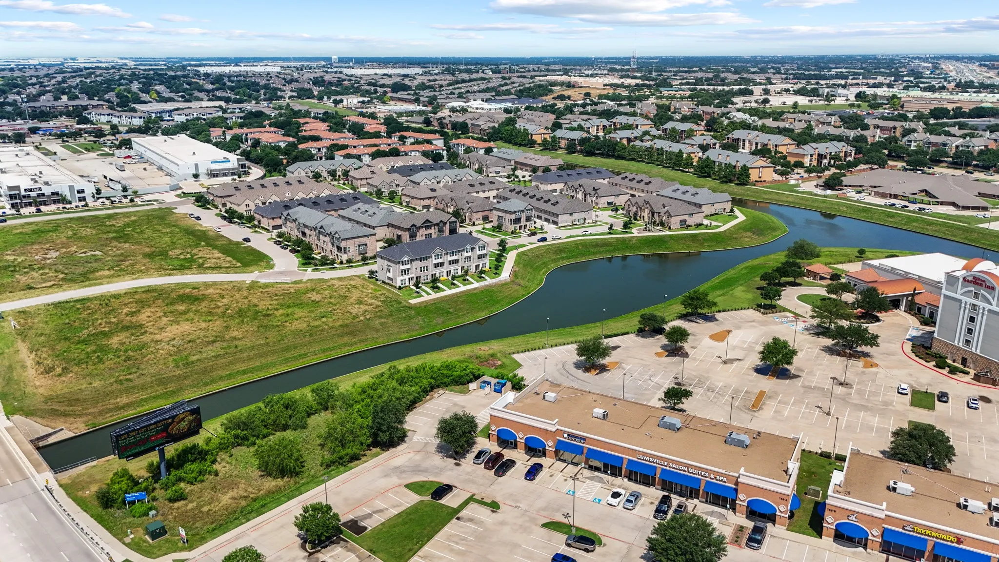 Aerial overview of the community featuring well-maintained brick townhomes, mature landscaping, and the signature canal that gives Vista Del Lago its distinctive character.