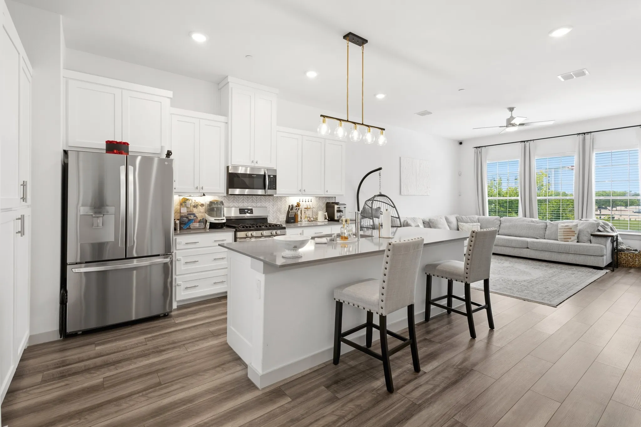 Well-appointed kitchen featuring a large center island, stainless French door refrigerator, premium white cabinetry, and an open layout that connects seamlessly to dining and living areas.