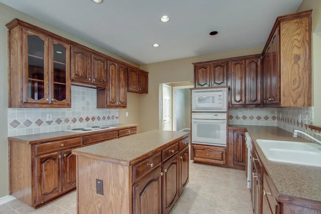Kitchen featuring wood cabinetry, a central island with countertop, a tile backsplash, recessed lighting, and a built-in oven and microwave