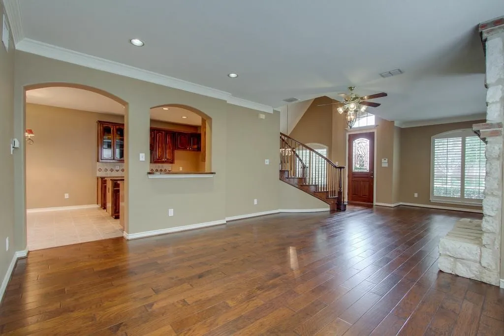 Expansive living area featuring wood-finish flooring, a stone-clad fireplace, and recessed lighting