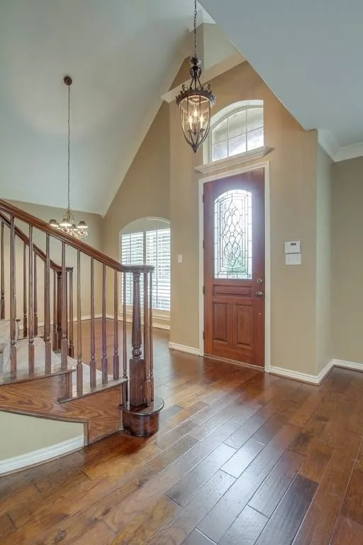 Entry foyer featuring wood-finish flooring, a vaulted ceiling, and a decorative chandelier