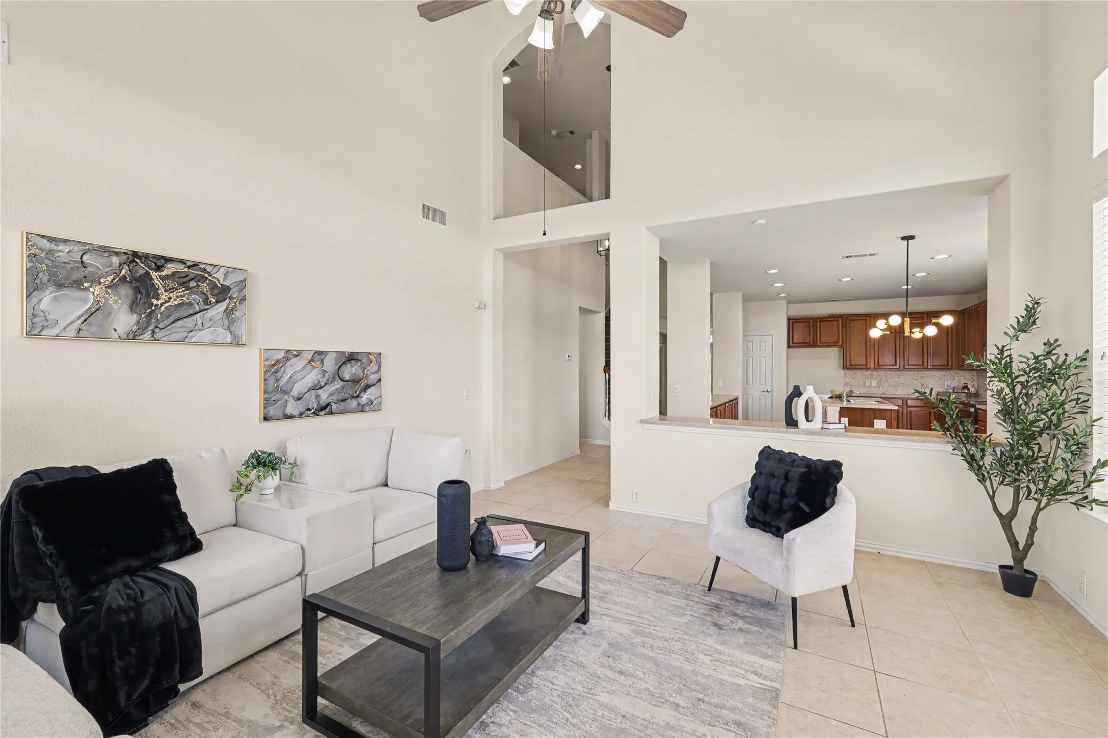 Living area featuring tall ceilings with a ceiling fan, a kitchen pass-through, and tile flooring