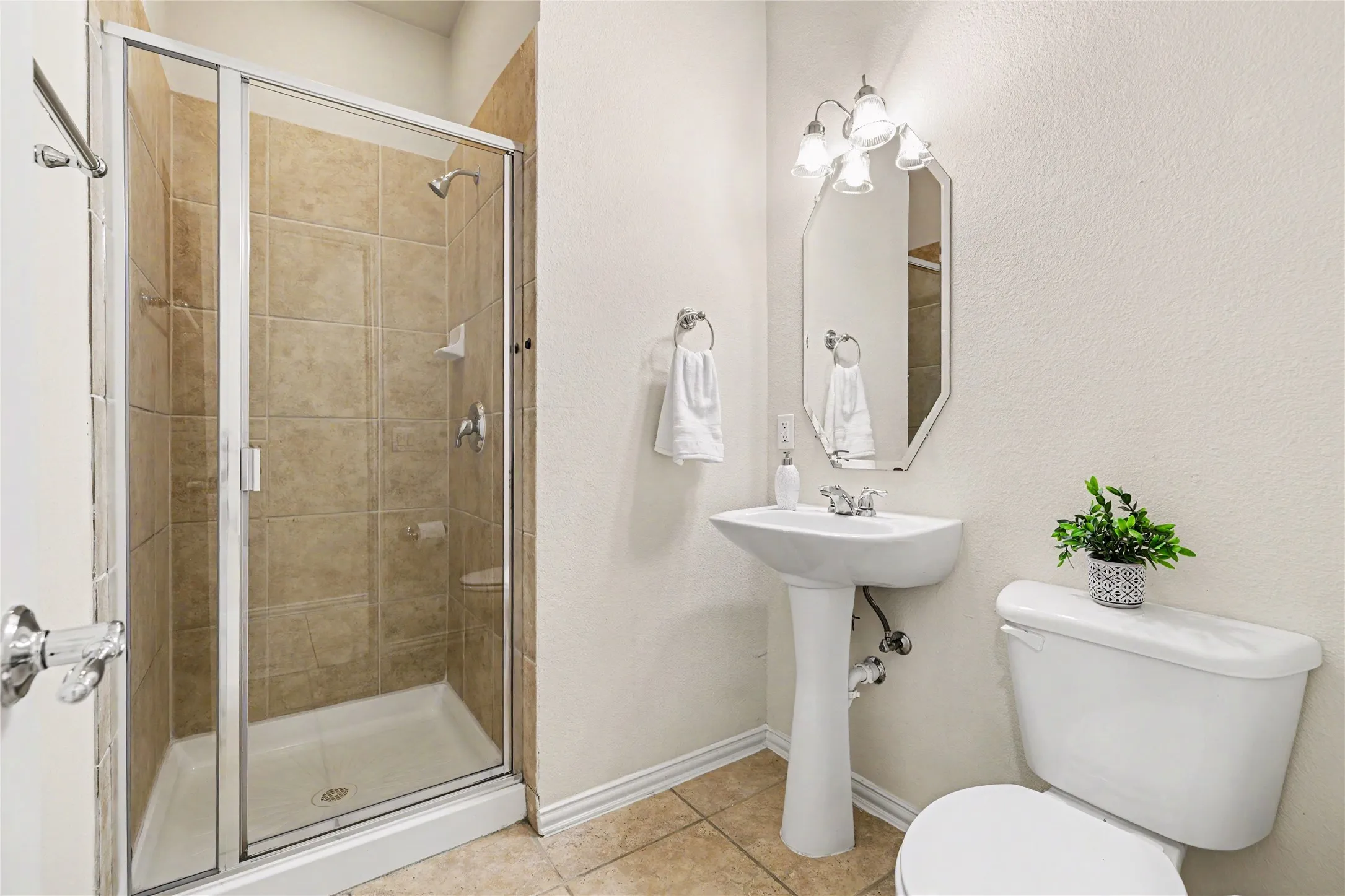 Shower enclosure featuring sliding glass doors and neutral-toned wall tiling