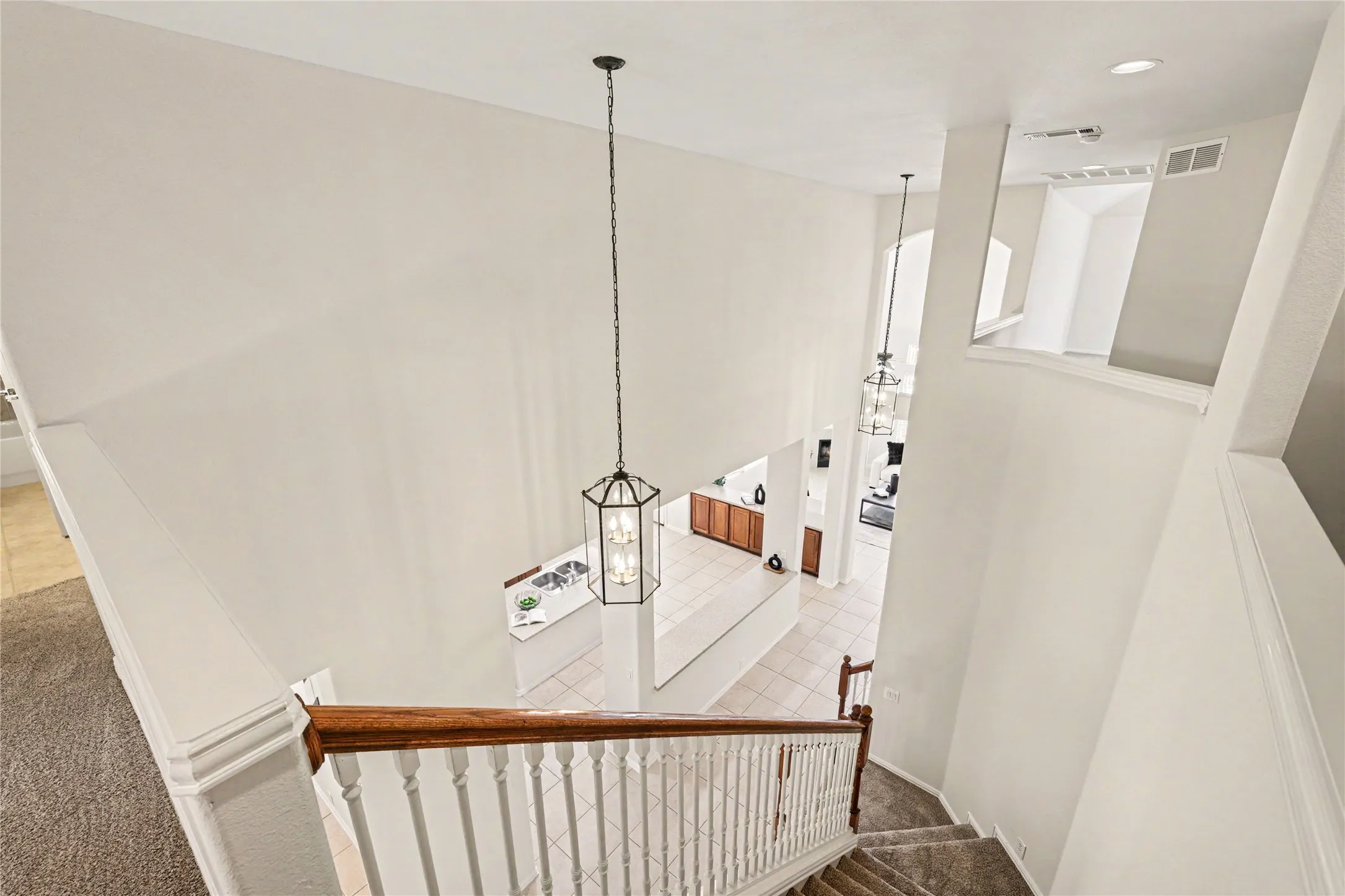 Two-story entryway with a carpeted staircase and wood-finish handrail