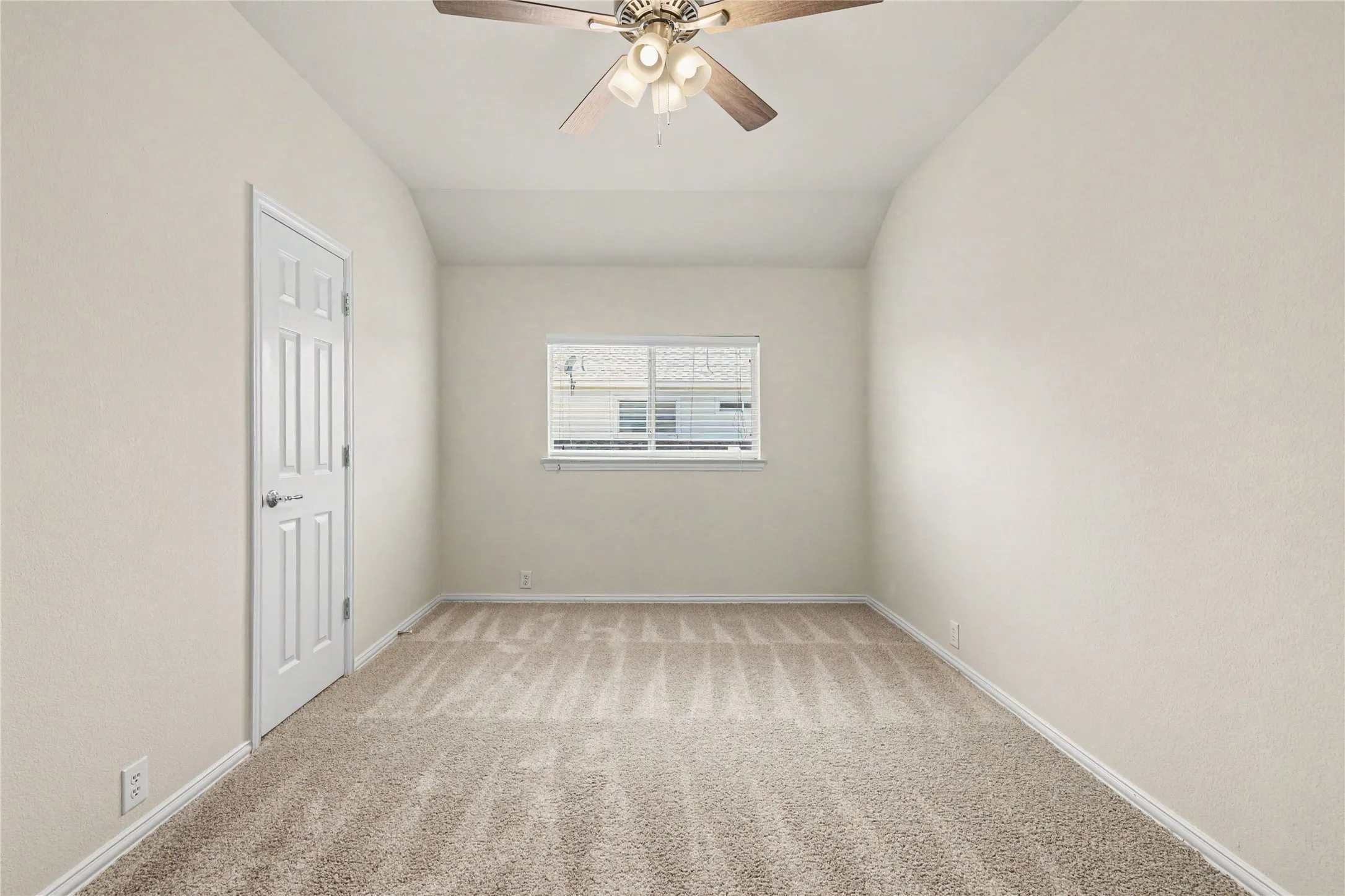 Carpeted room featuring a ceiling fan with light fixture, a window with blinds, and a paneled door