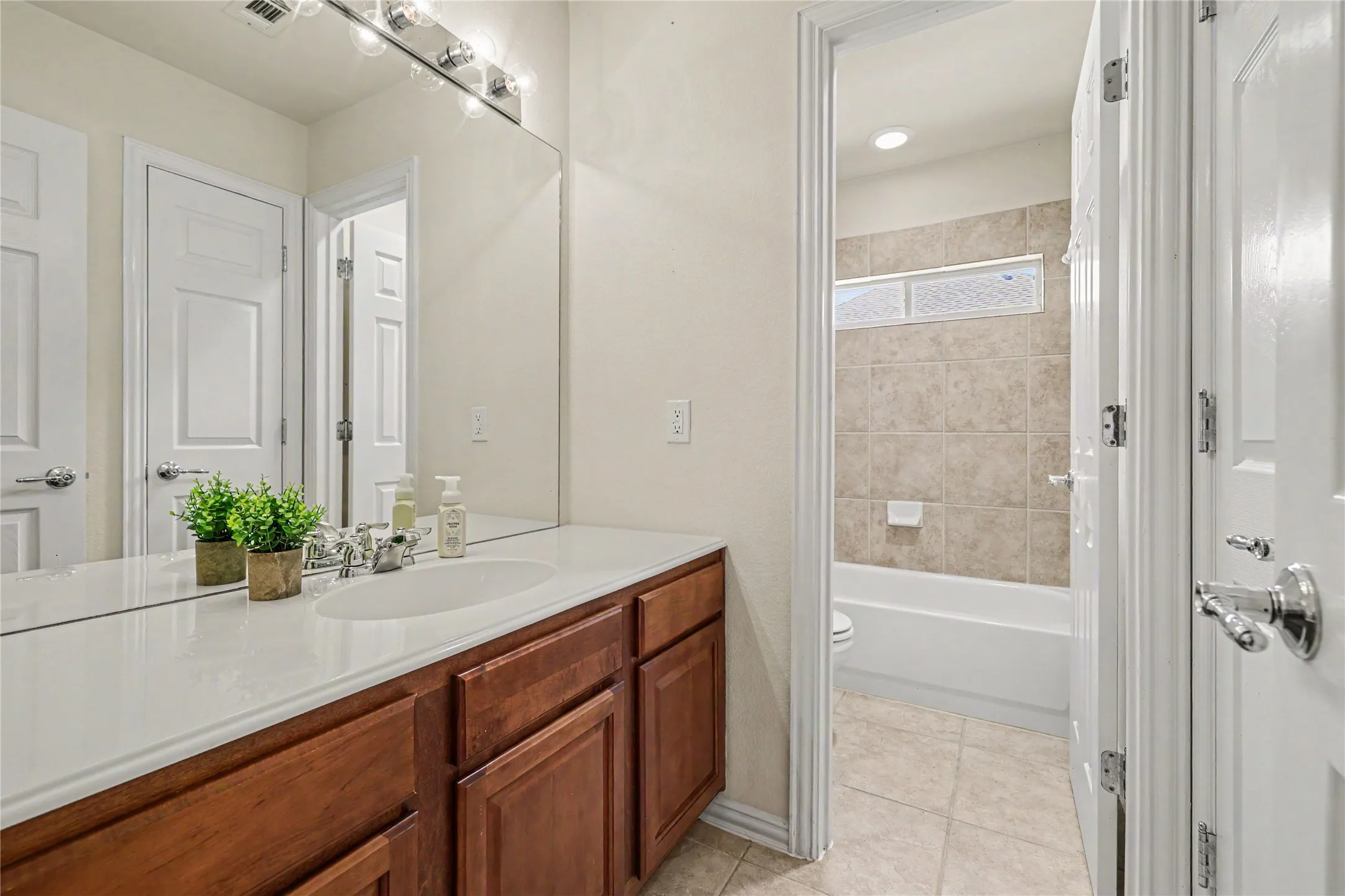 Bathroom vanity featuring a single undermount sink, a white countertop, and wood-finish cabinetry