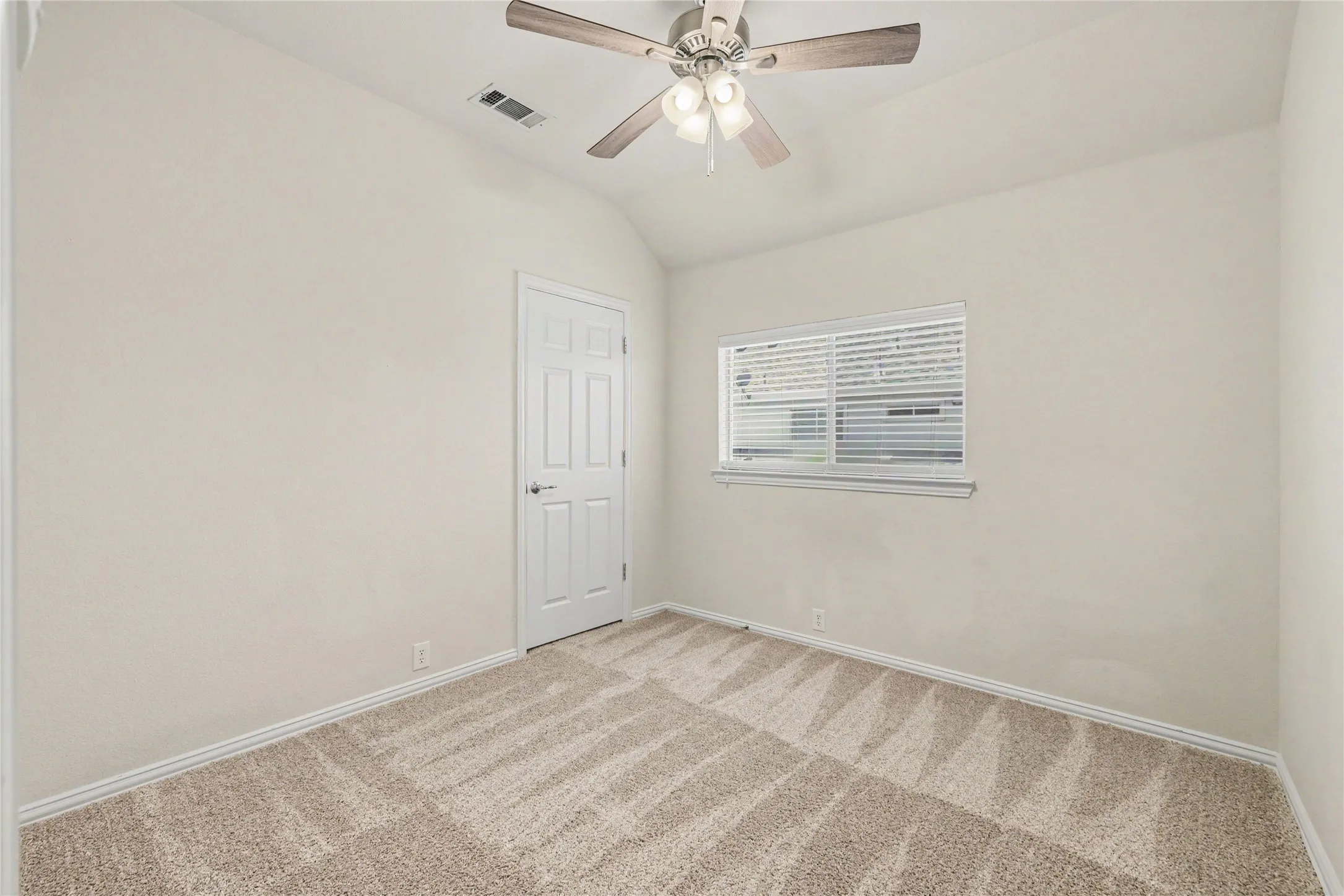 Neutral-toned carpeting and walls complement the vaulted ceiling