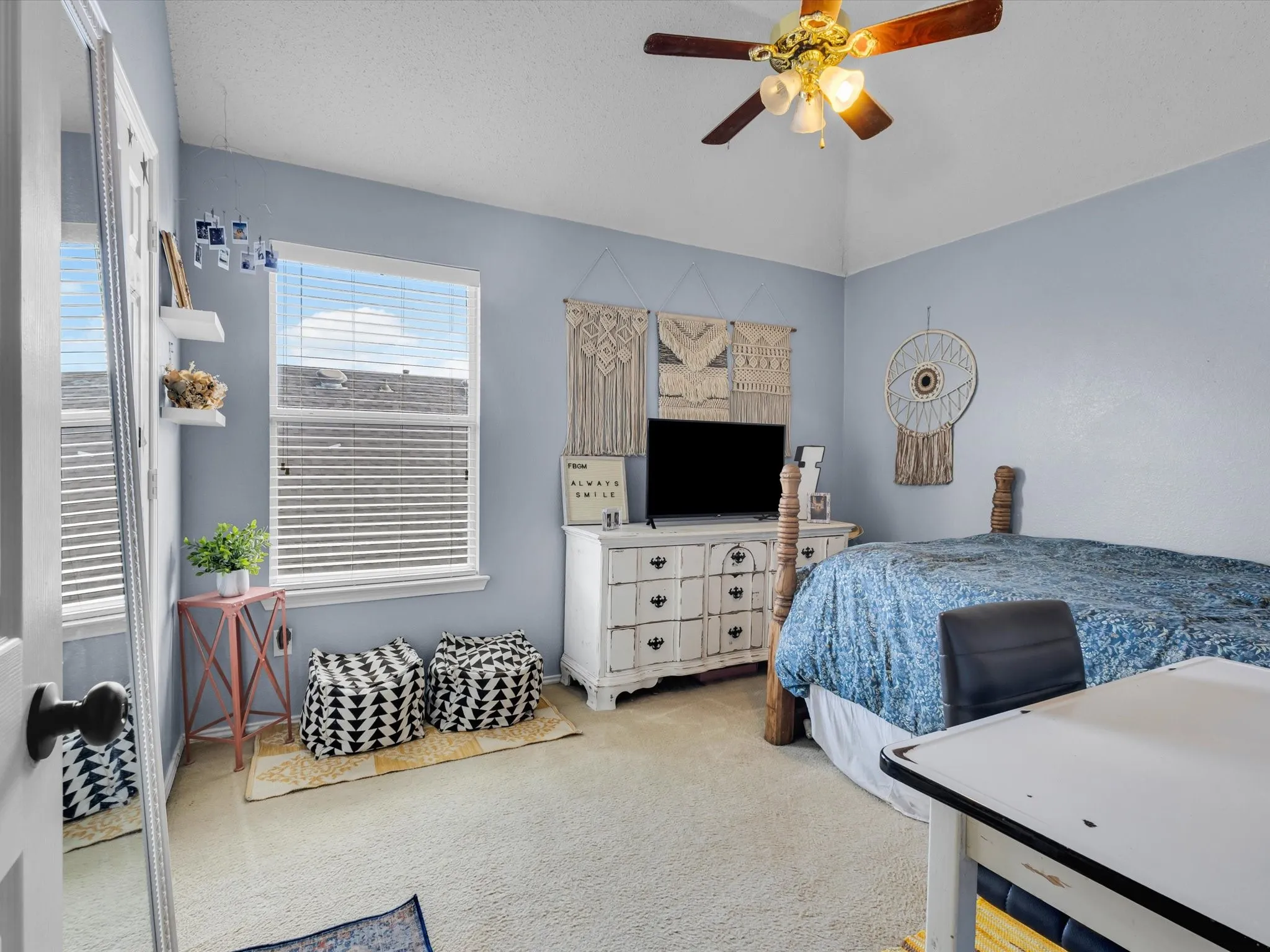 Vaulted ceiling with a ceiling fan, carpeted flooring, and a large window with horizontal blinds