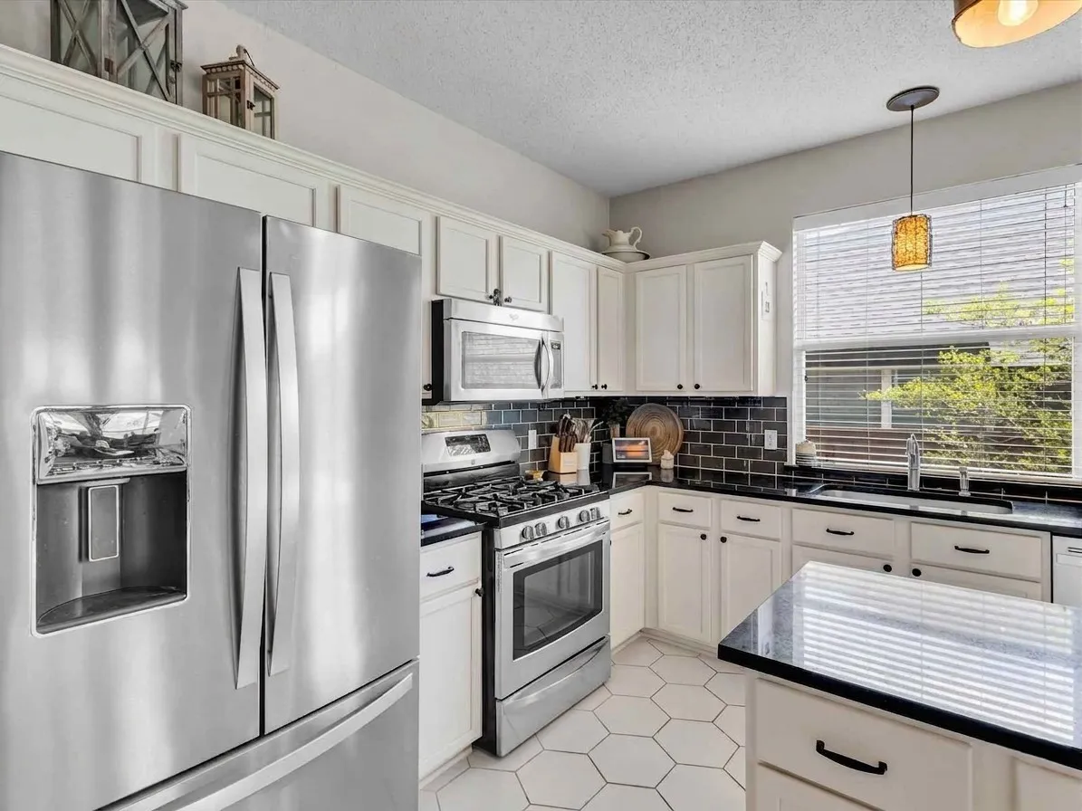 Kitchen featuring stainless steel appliances, white cabinetry, dark countertops, and a subway tile backsplash