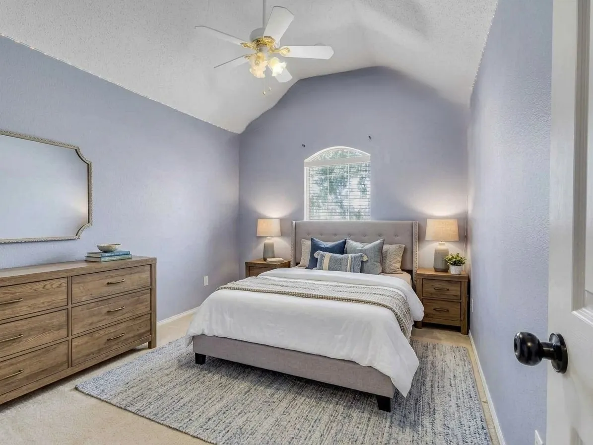  Room featuring a vaulted ceiling with a ceiling fan, an arched window with blinds, and light-colored walls. This bedroom photo is virtually staged.