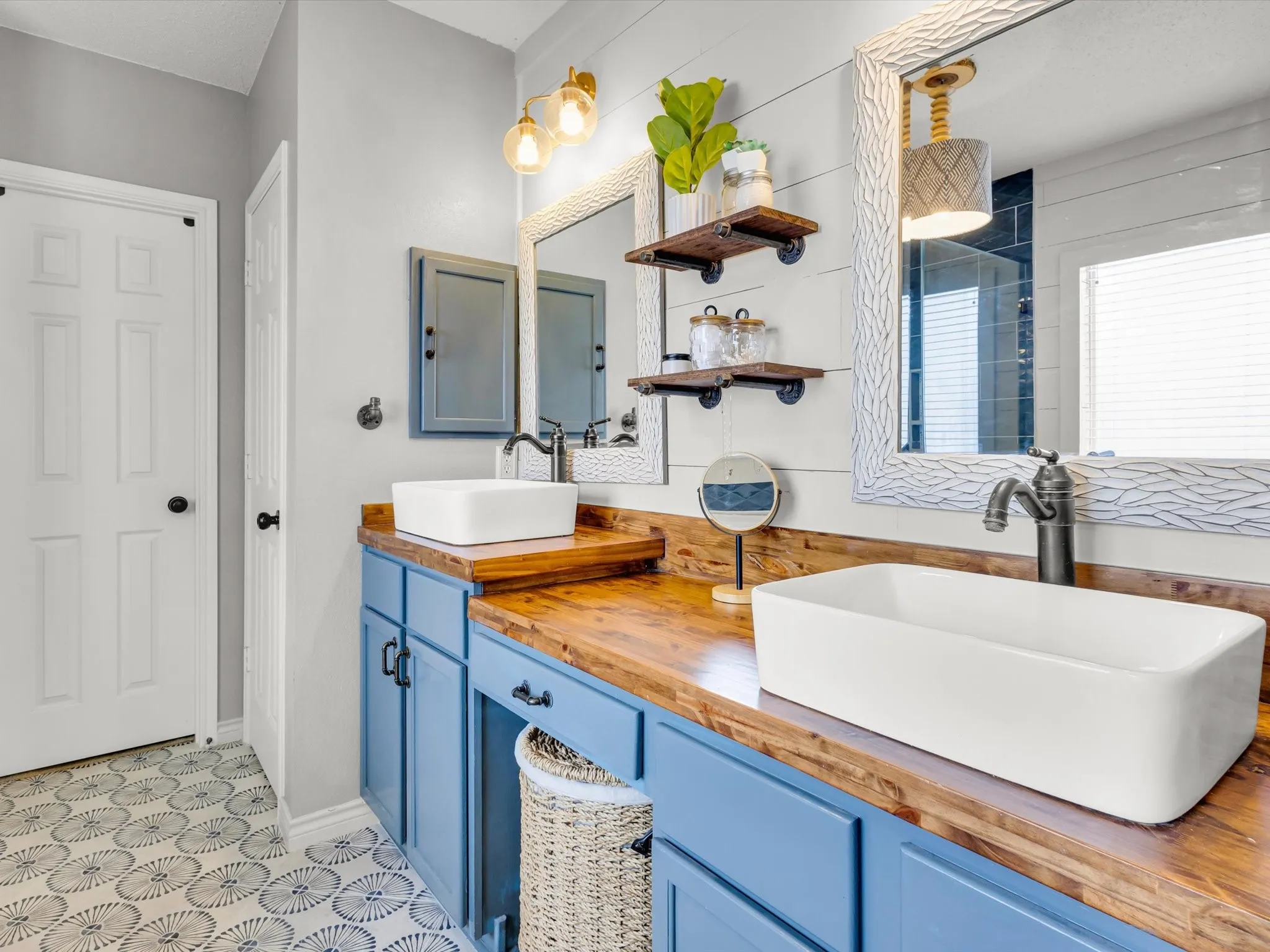 Dual vessel sinks set on a wood-finish countertop with blue cabinetry