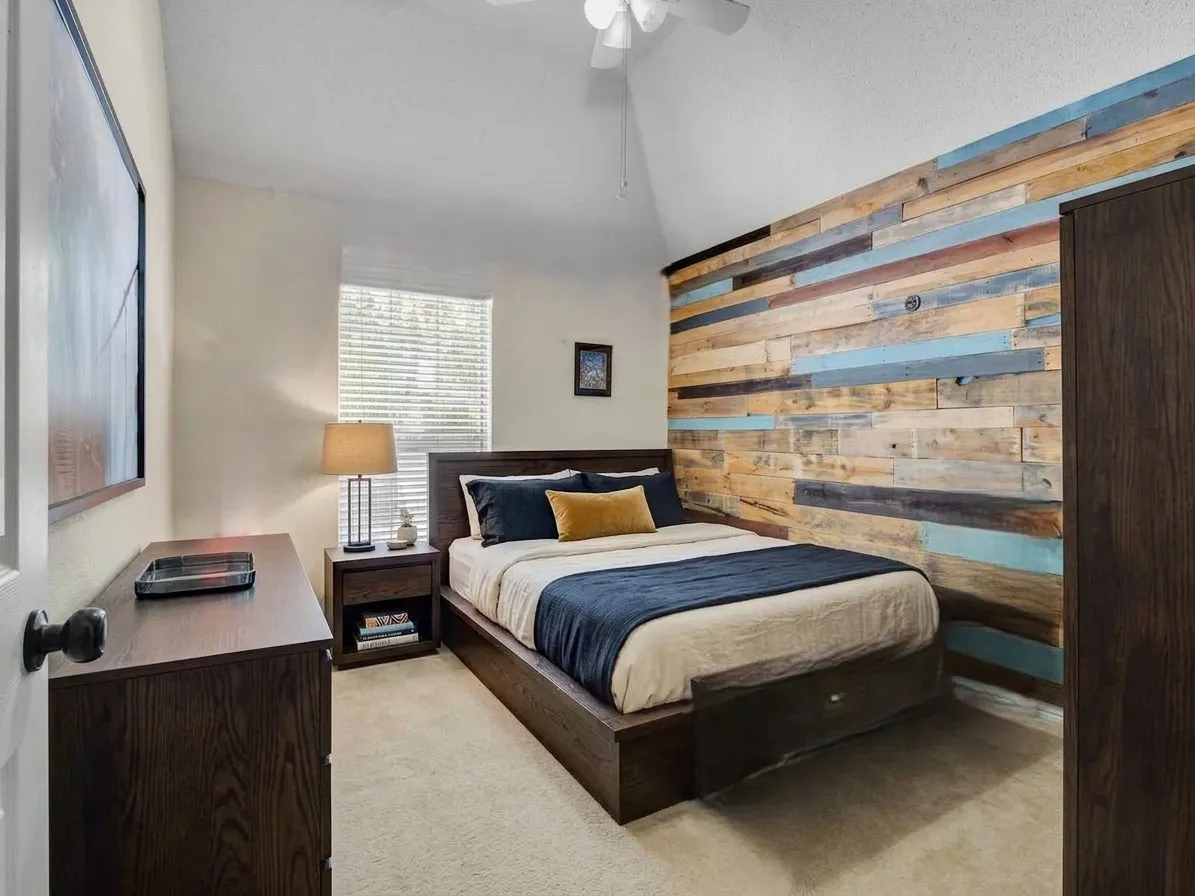 Accent wall featuring multi-toned wood paneling. This bedroom photo is virtually staged.