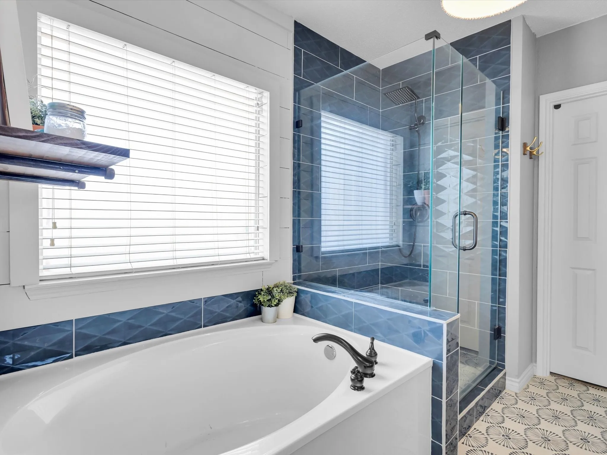 Soaking tub with dark bronze-finish fixtures, framed by decorative blue tile