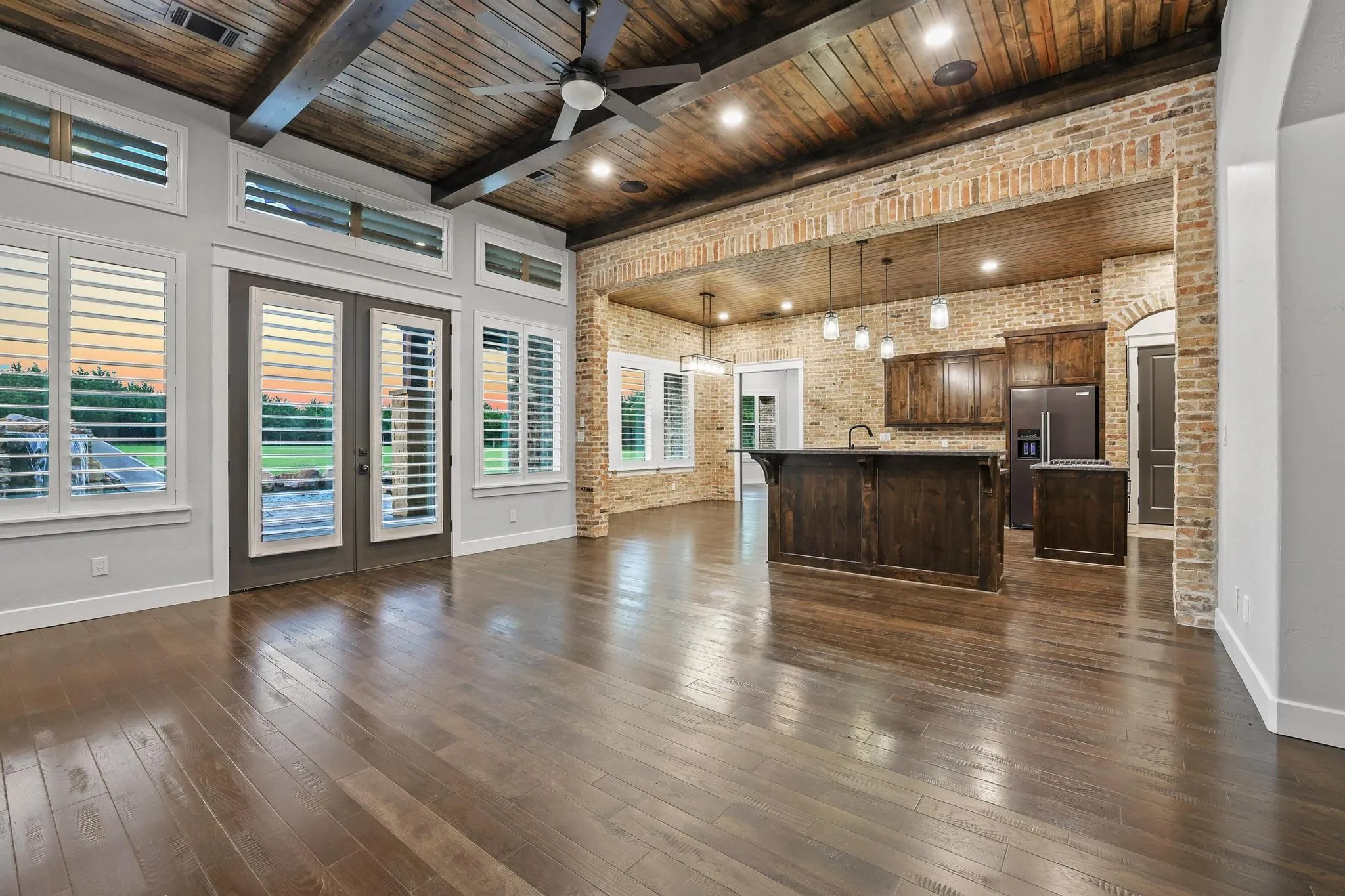 Spacious living area featuring wood-finish flooring, a wood plank and beam ceiling with recessed lighting, and a ceiling fan