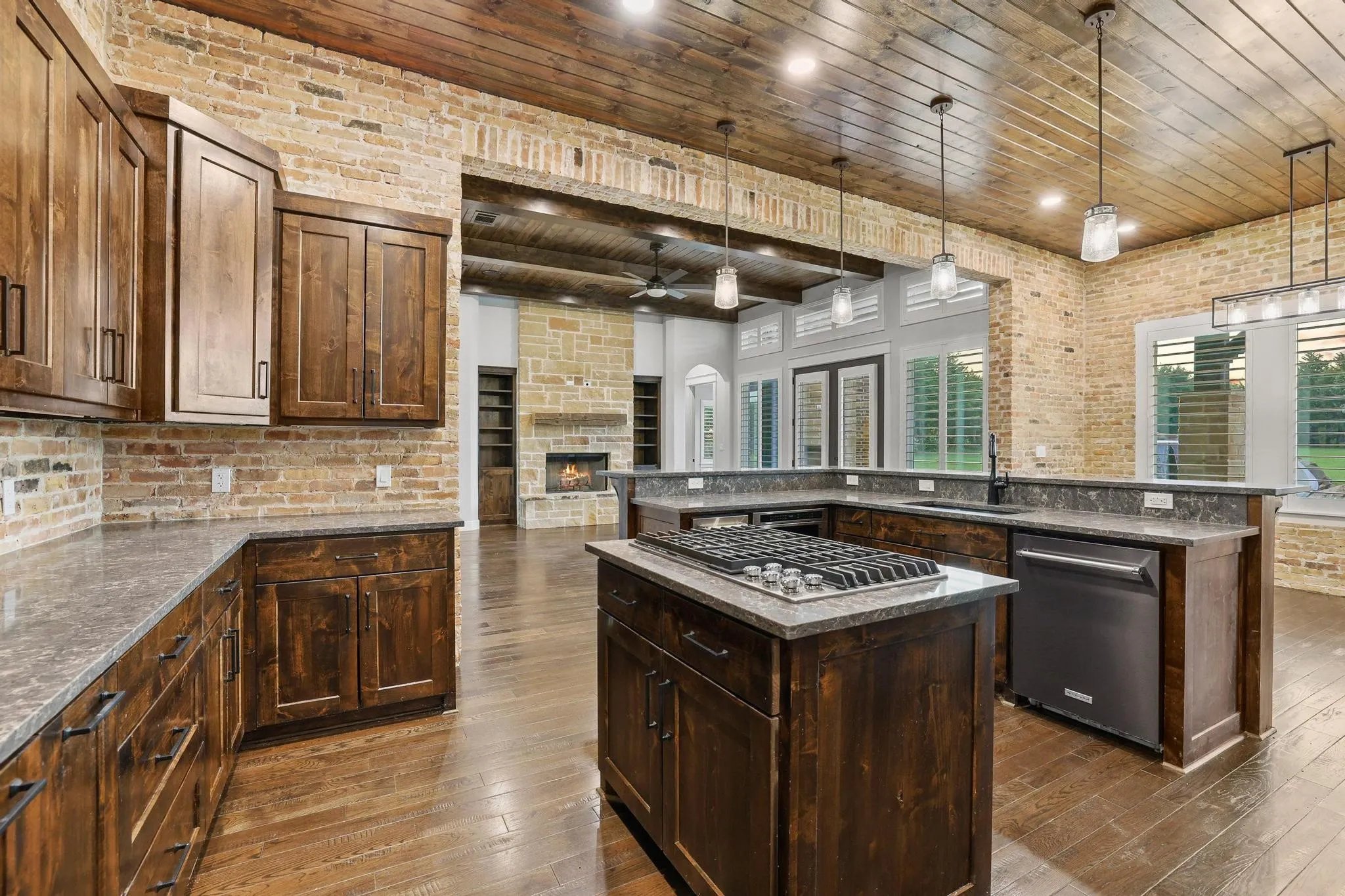 Open-concept kitchen with dark wood cabinetry, a central island featuring a gas cooktop, and light-toned countertop surfaces