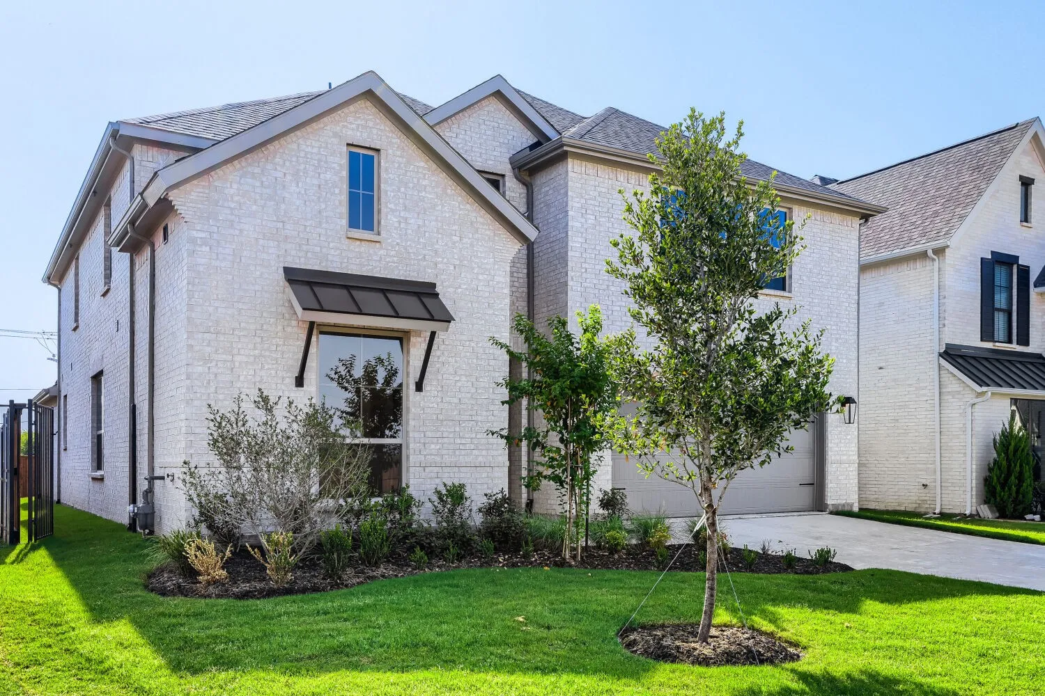 White painted brick exterior with dark shingle roofing and a prominent garage