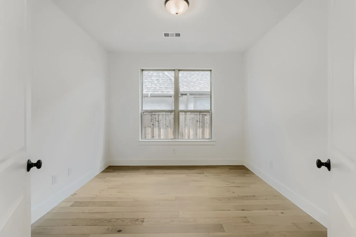 Recessed window with white trim, wood-finish flooring, white walls, and a ceiling-mounted light fixture