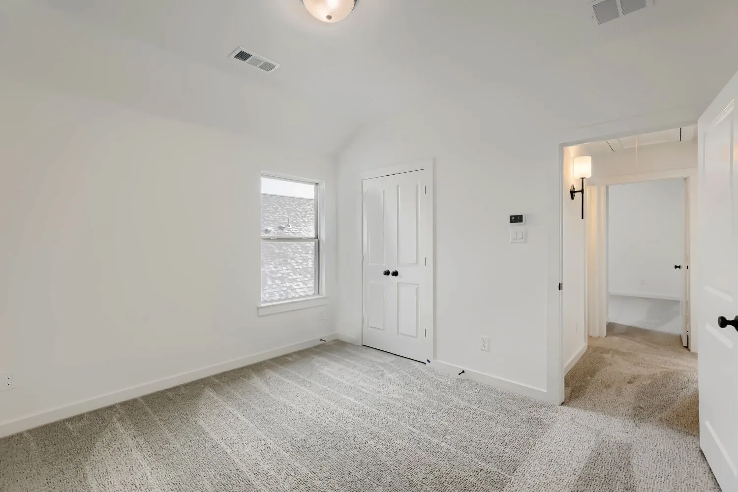 Bright secondary bedroom featuring vaulted ceilings, recessed lighting, and a large window providing natural illumination
