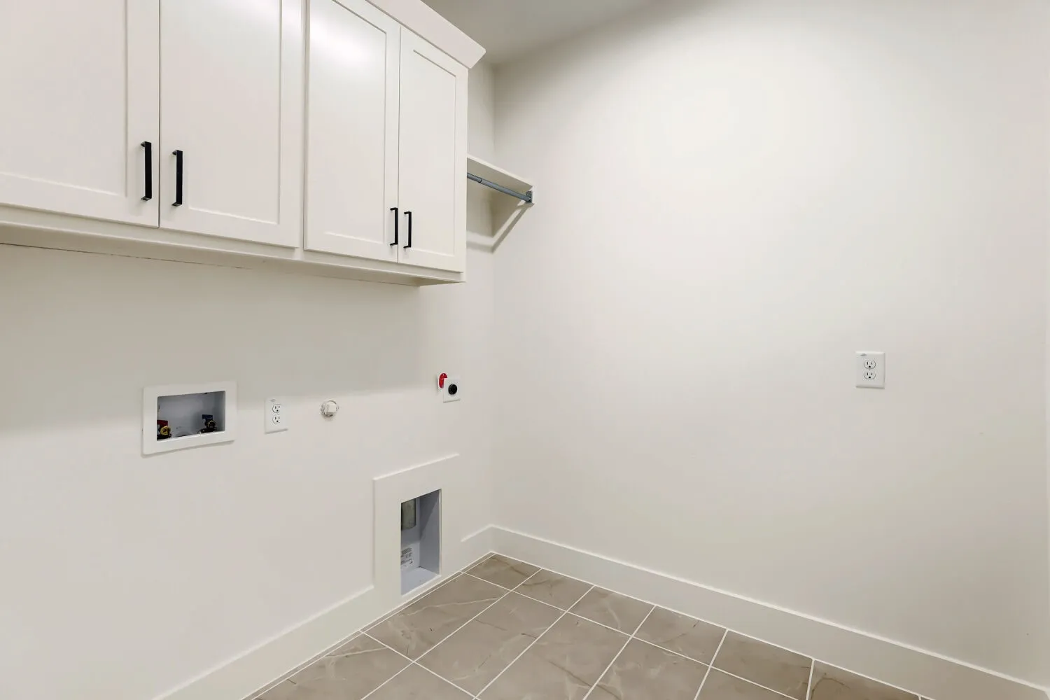 White shaker cabinetry with black hardware, an integrated hanging rod, and tile flooring