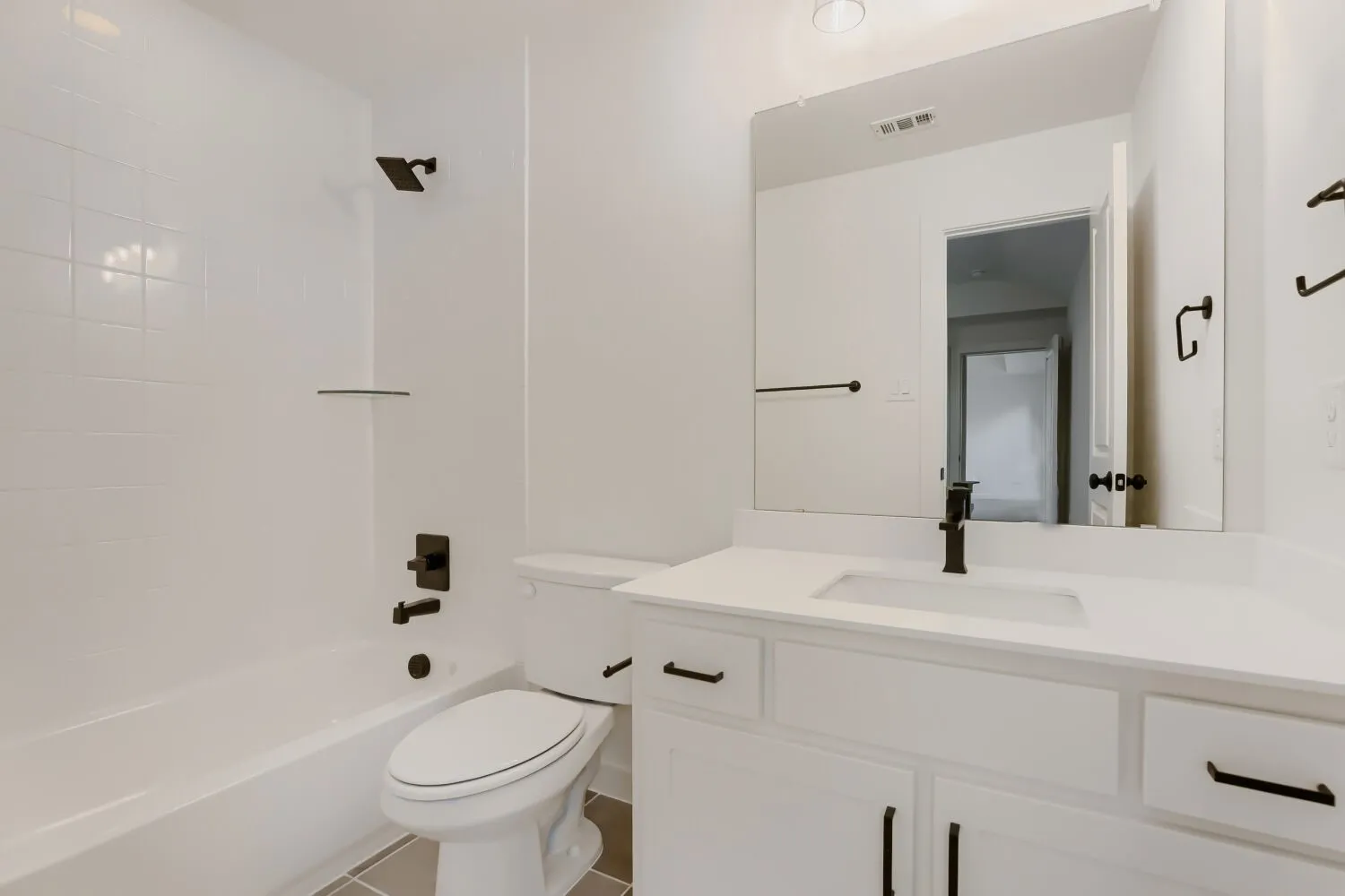 White vanity with a rectangular undermount sink, a large mirror, and matte black fixtures