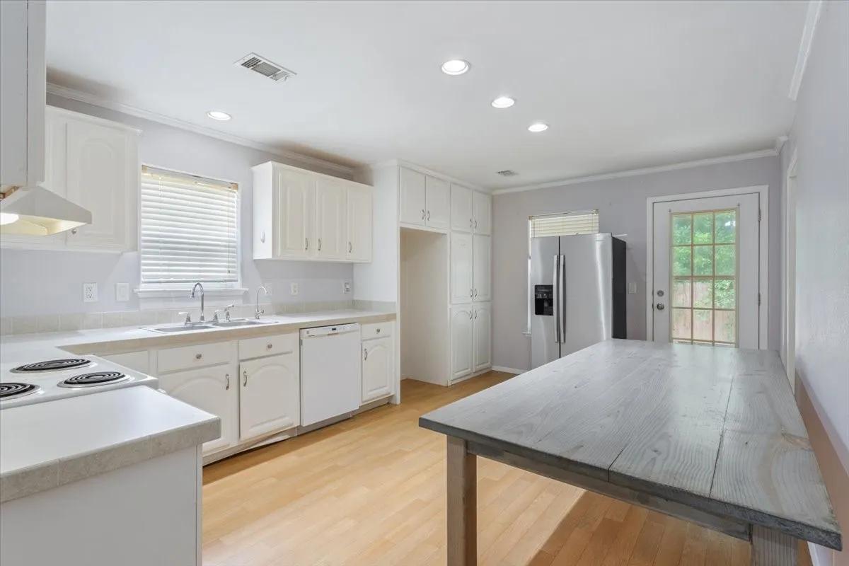 Kitchen featuring light wood-finish flooring, white cabinetry, a built-in dishwasher, and recessed lighting