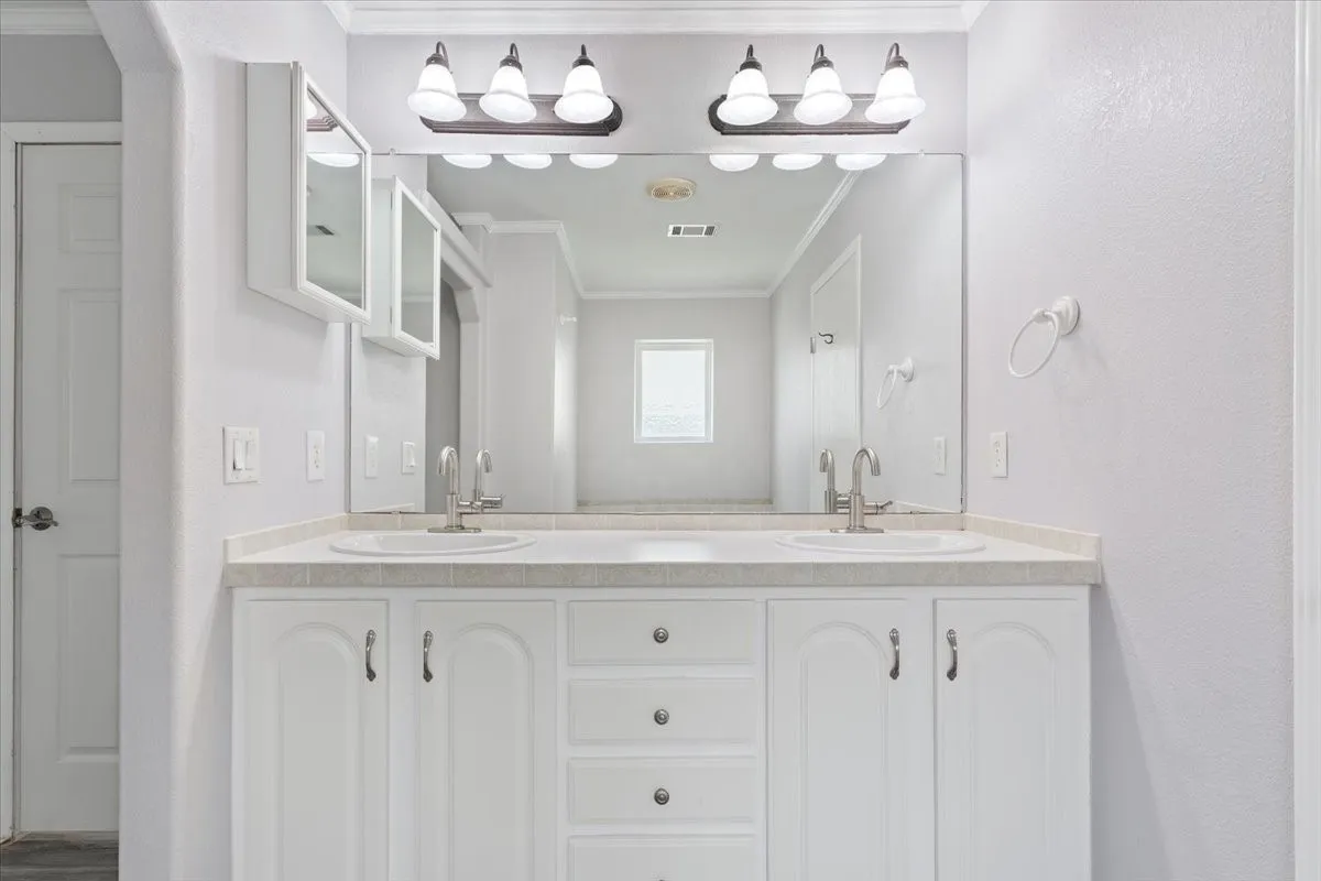 Double vanity with white cabinetry, dual undermount sinks, and laminate countertops