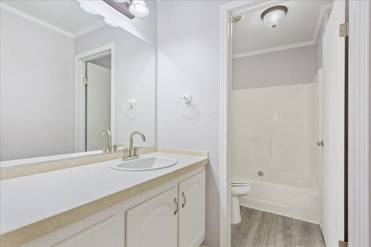 Bathroom vanity with an integrated sink, brushed nickel faucet, and a large wall-mounted mirror