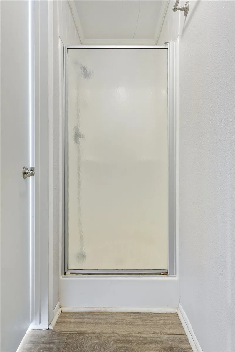 Bathroom shower with a frosted glass enclosure, chrome frame, and a white shower base