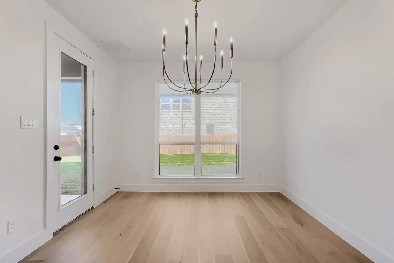 Warm wood-finish flooring, a contemporary chandelier, and a glass-paned door