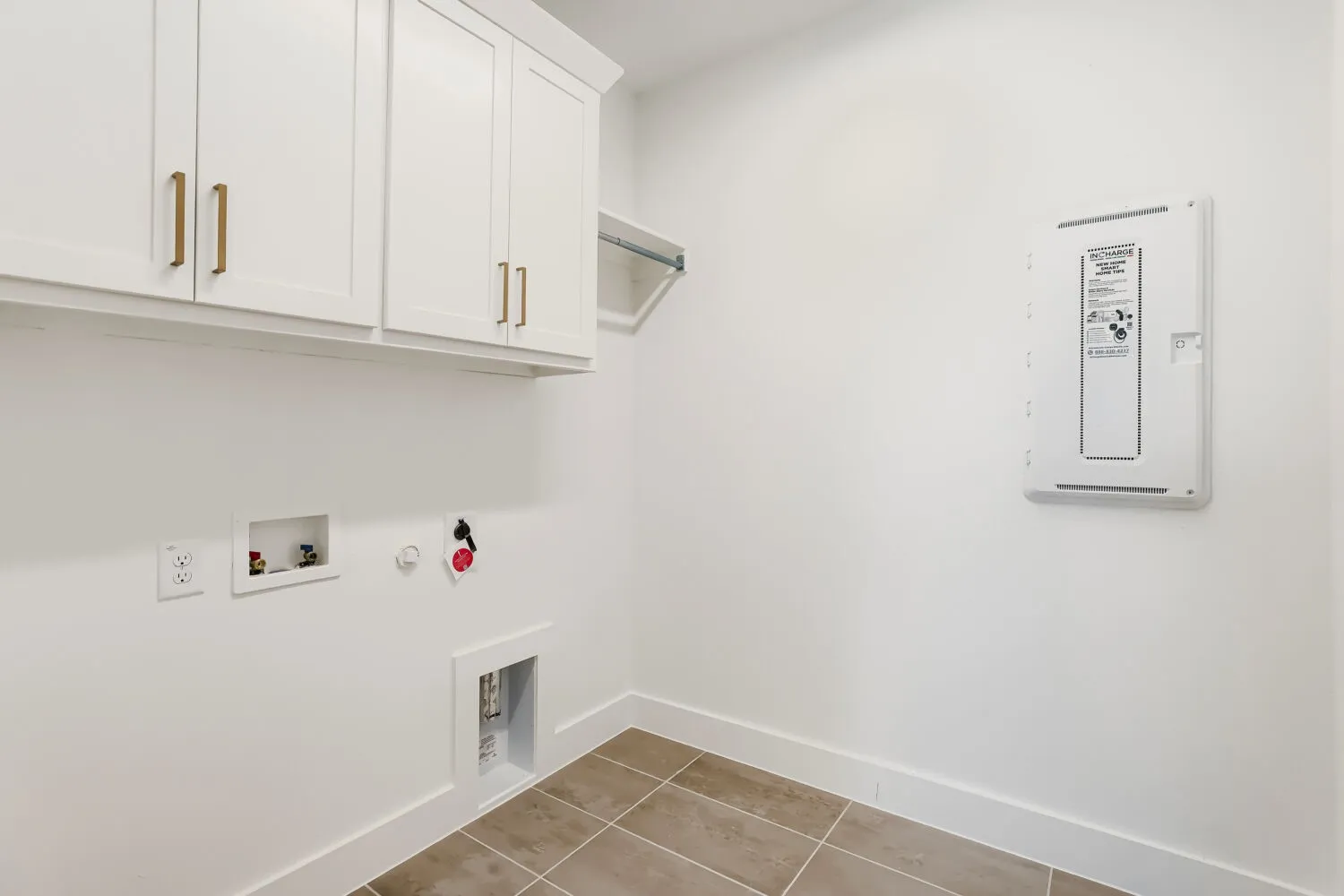 White shaker-style cabinetry with gold-tone hardware, a wall-mounted wire shelf, and large format floor tiling