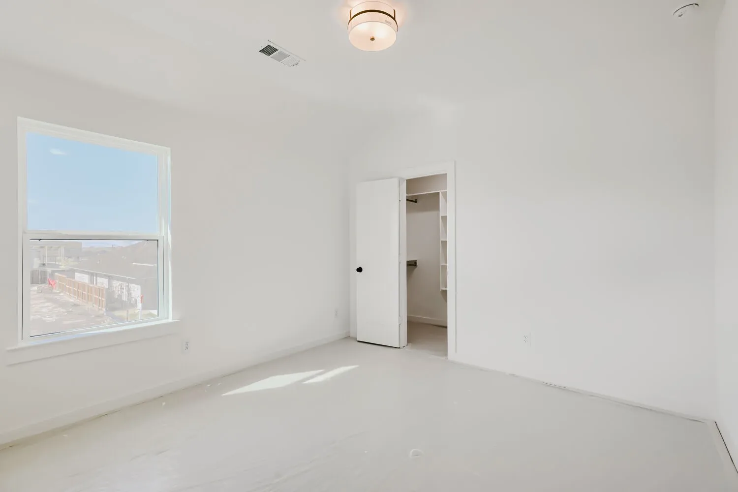 White walls with a single window, a flush-mount ceiling light fixture, and an open closet featuring built-in shelving