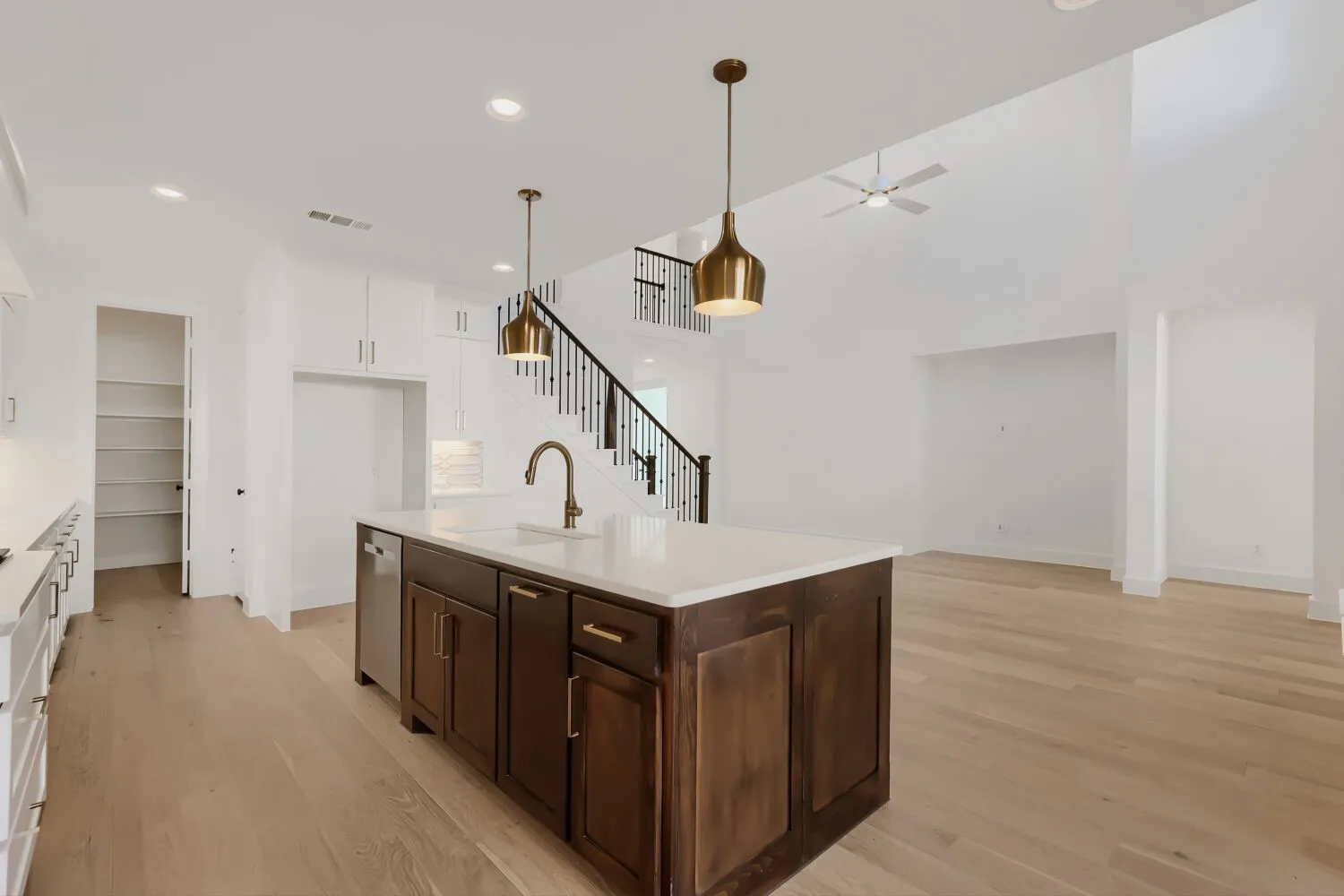 Kitchen island with a white countertop and dark wood-finish cabinetry, featuring a built-in sink with a gooseneck faucet
