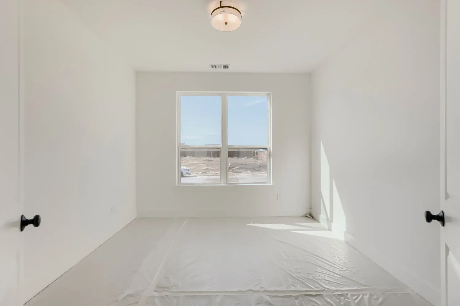 Recessed window with exterior views, overhead flush mount lighting, and matte black door hardware