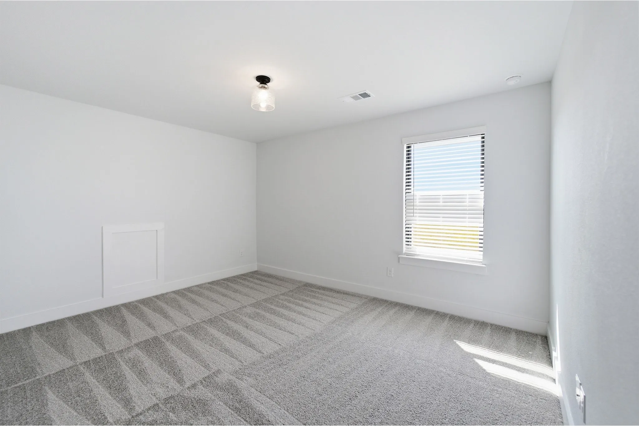Room featuring neutral wall tones, patterned carpet flooring, a single window with blinds, and a flush-mount ceiling light fixture